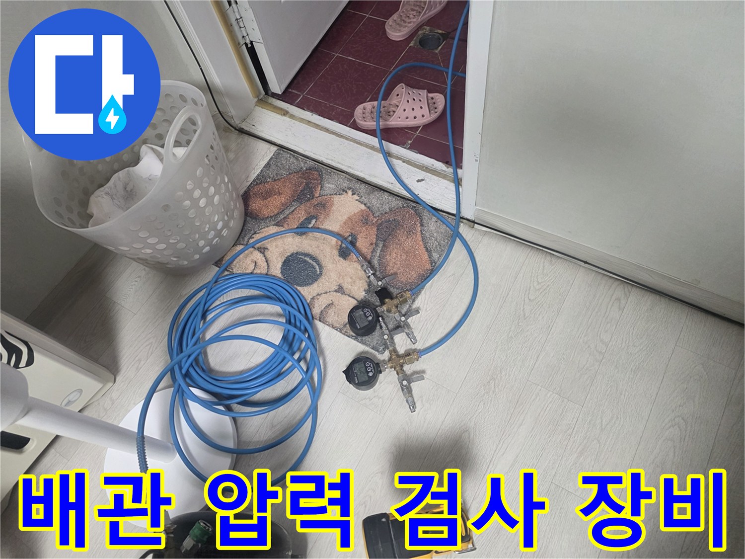 누수 점검을 위해 바닥에 설치된 공기압 테스트 장치와 파란색 호스