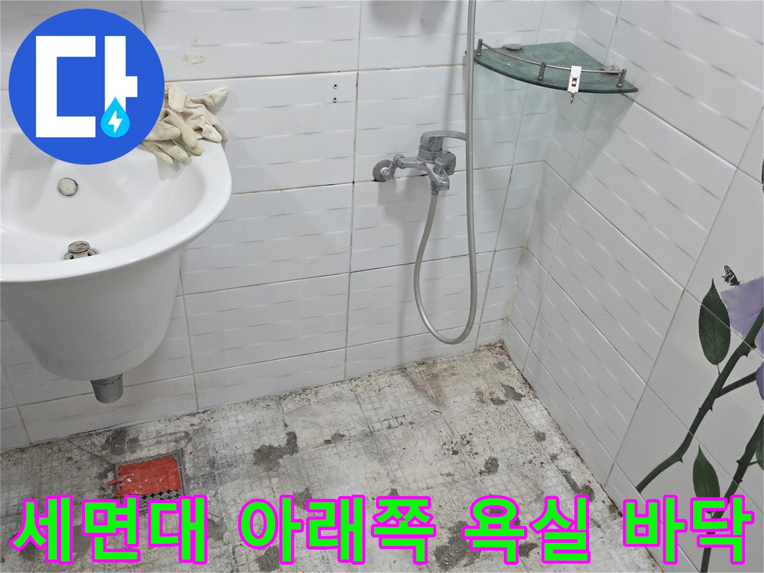세면대 하단부의 젖은 타일과 배수구 주변 모습