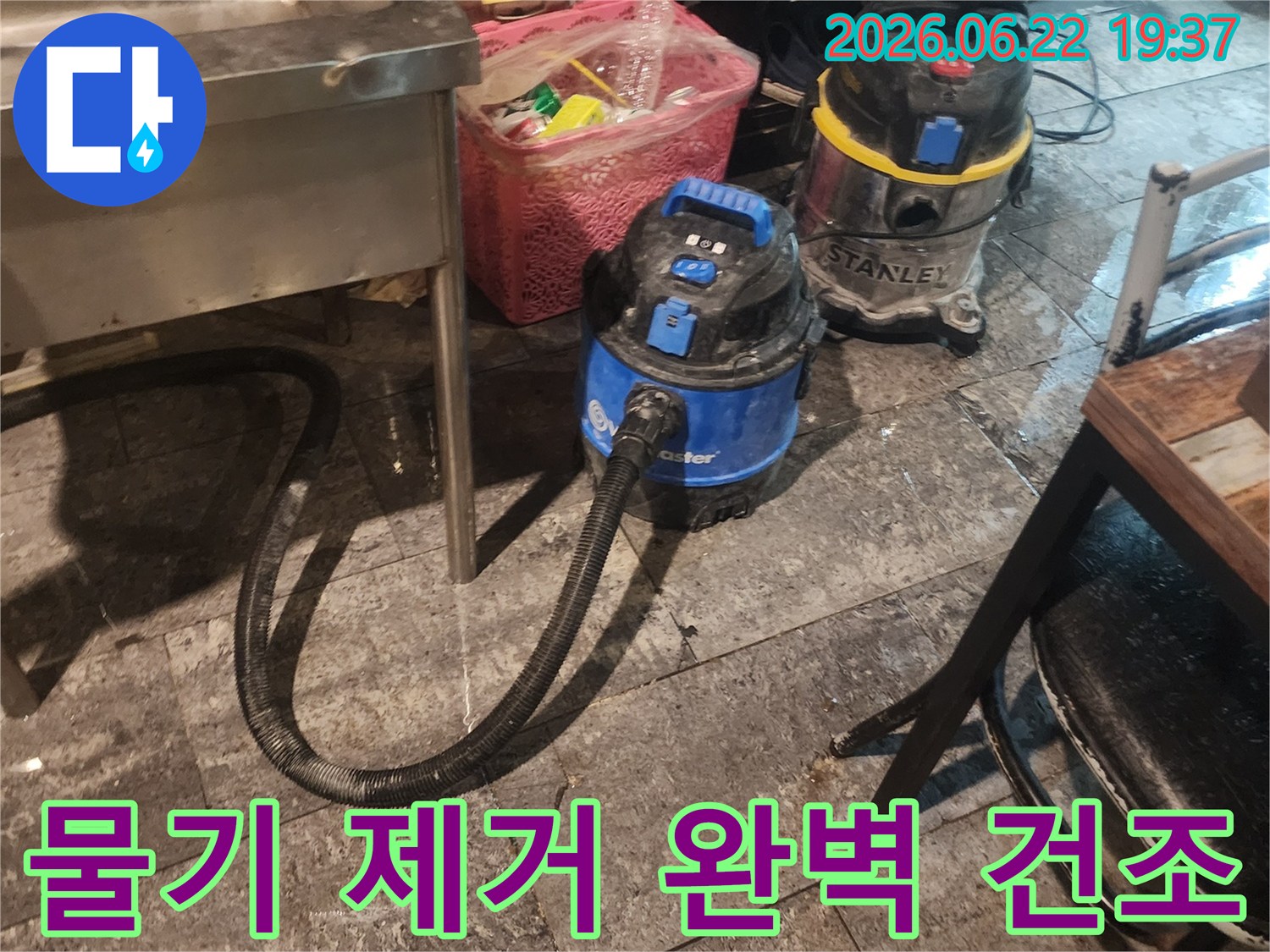 누수-현장에서-바닥의-물을-흡입하여-건조-작업을-준비하는-두-대의-산업용-청소기-장면입니다