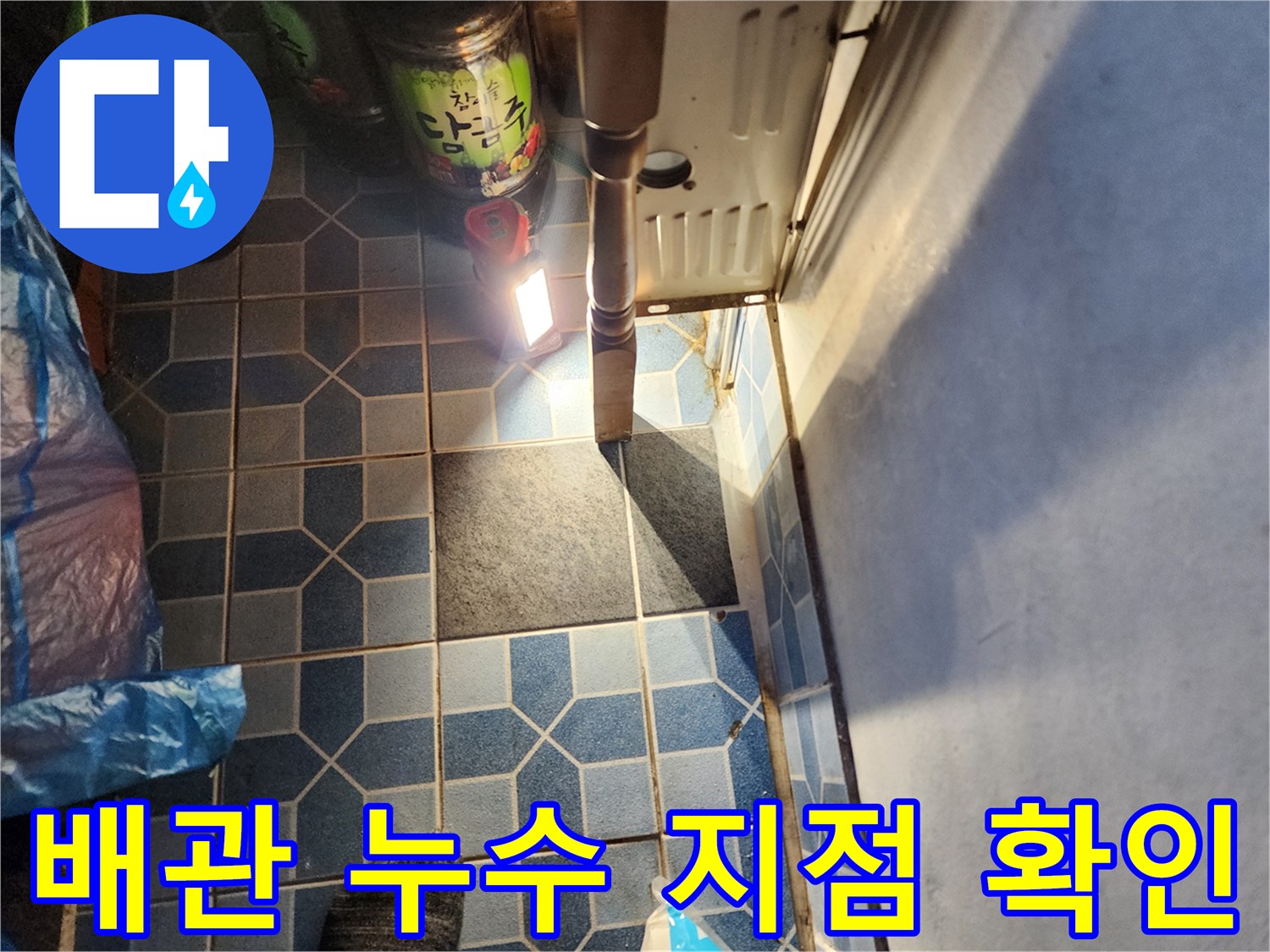 보일러실 바닥-조명을 활용하여 배관 연결 부위의 결함을 찾는 작업 현장