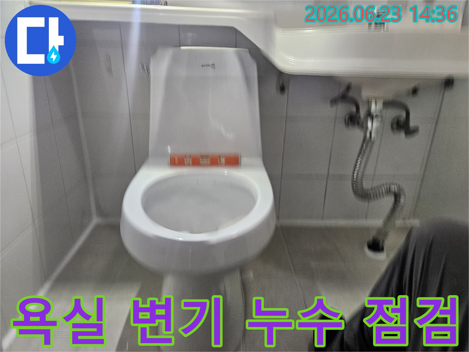 이 사진은 욕실 변기 주변에서 발견된 물샘 현상을-전문가가 면밀히 조사하는 과정을 담고 있습니다.