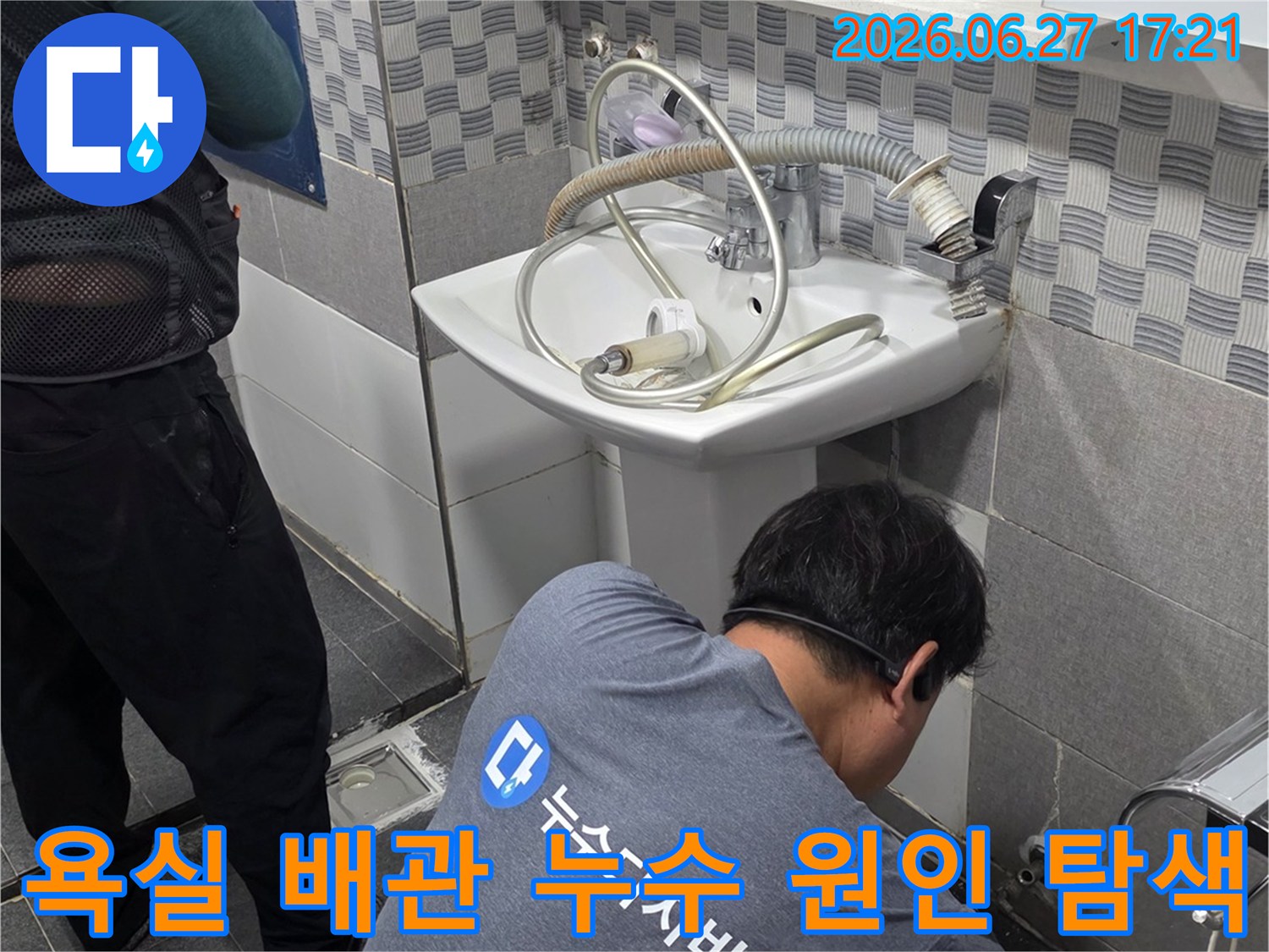 전문 엔지니어가- 욕실 세면대 하부의- 복잡한 배관 시스템을- 면밀히 검토하고 있습니다.
