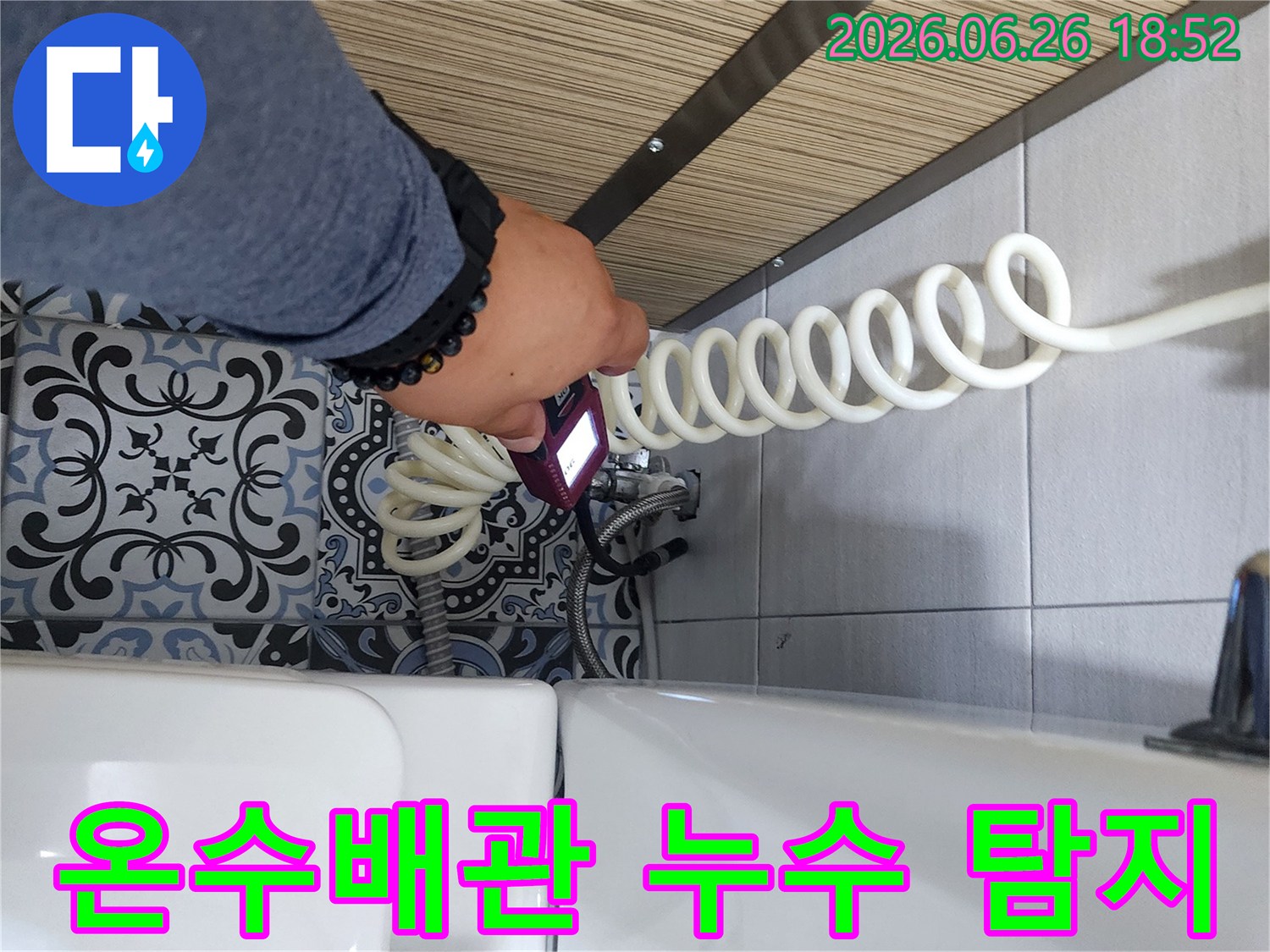 누수 엔지니어가 욕실 변기 옆 온수배관에서 전문 탐지 장비로 물샘 지점을 확인하고 있습니다.