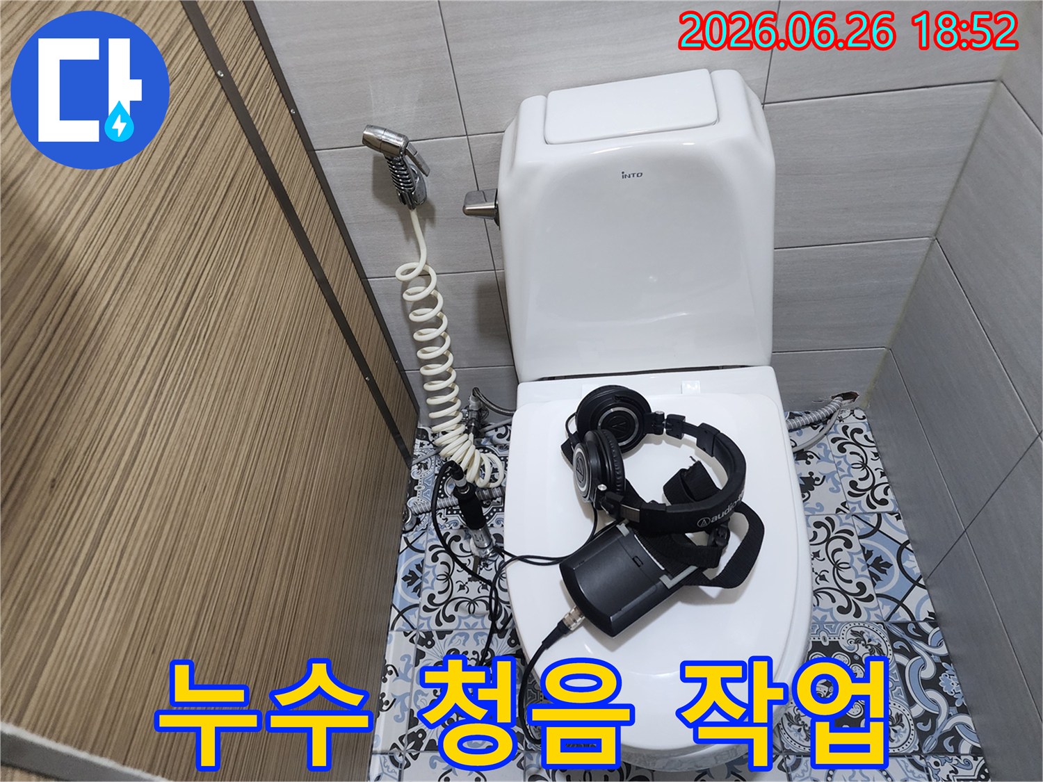 변기 위에 놓인-누수 탐지 장비와-헤드셋을 통해-누수 소리를-듣는 모습