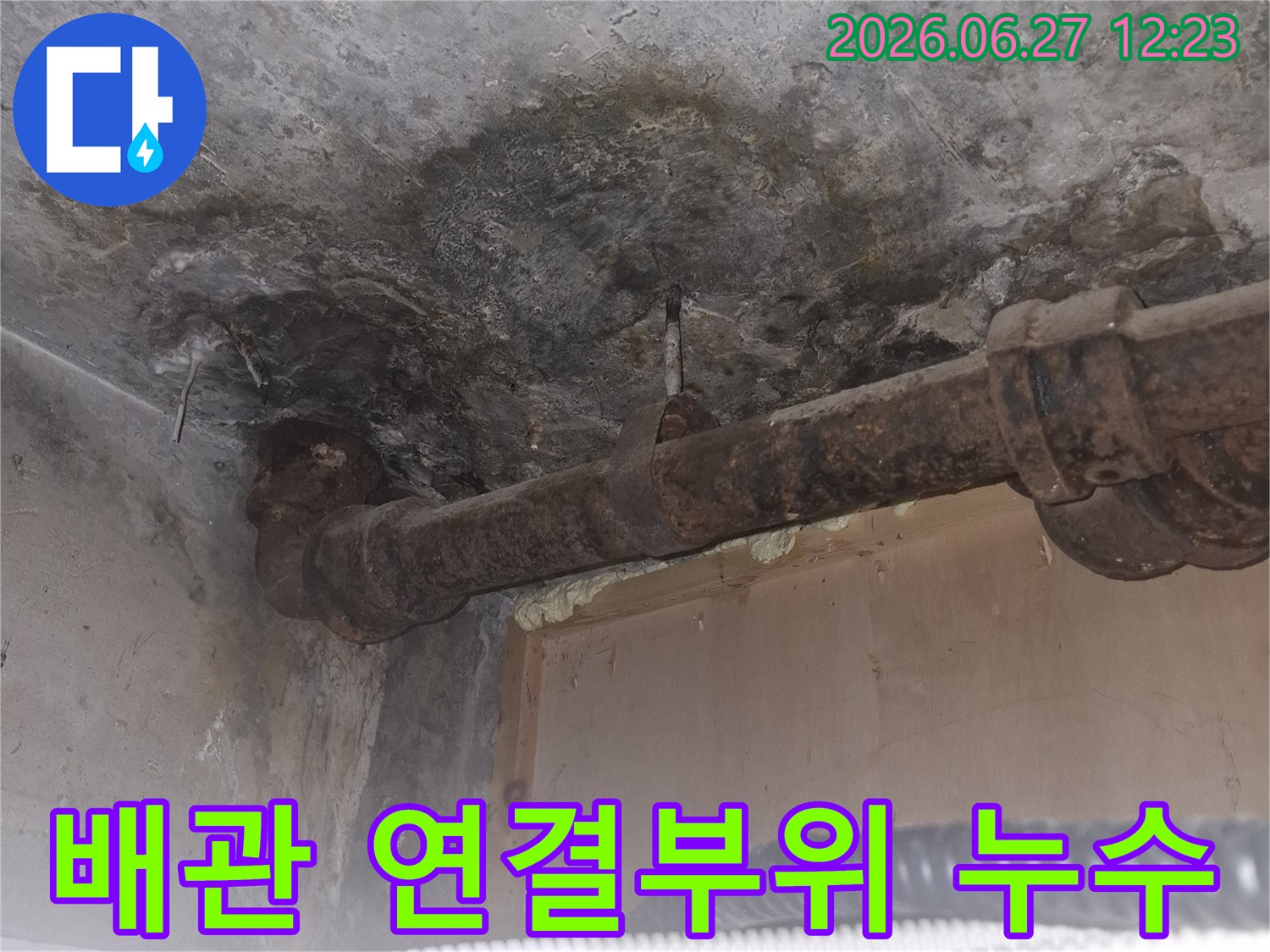 오래된 아파트의-녹슨 배관 연결부위에서-발생한 누수 흔적을-보여주는-젖은 콘크리트 바닥과-부식된 파이프의-상세 이미지입니다