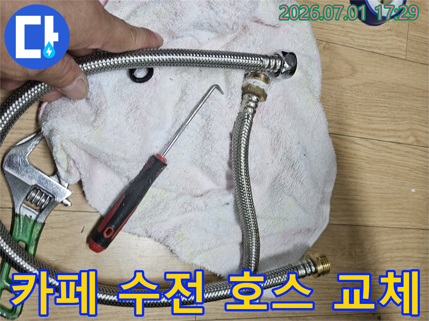 이 이미지는 카페 싱크대 수전 연결 호스 교체를 위해-새로운 호스와 작업 도구를 준비하는 현장입니다
