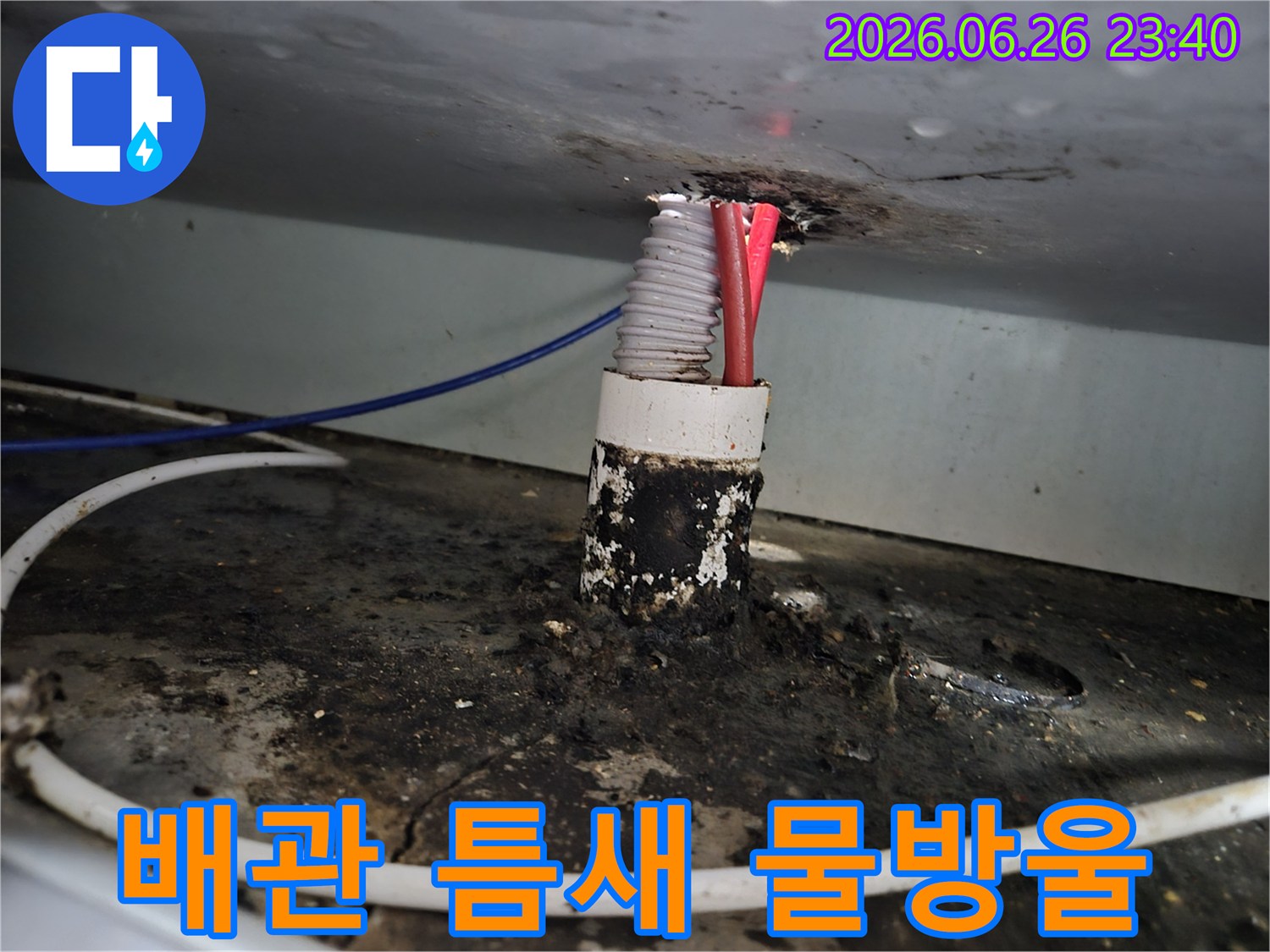 아파트 배관 주변의 오염된 틈새에서-물방울이 맺히고 있는 누수 현장을 보여주는 이미지입니다.