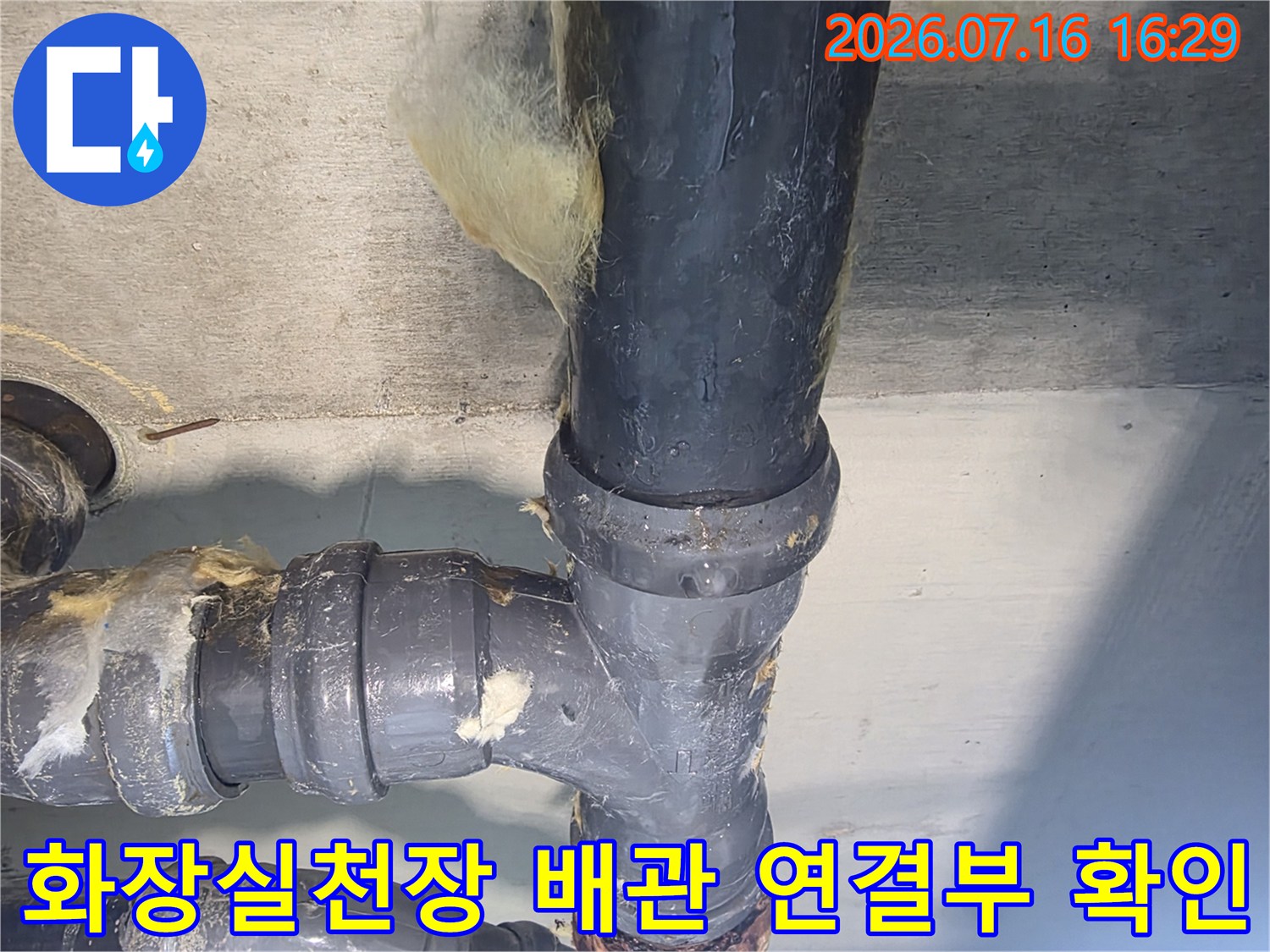 화장실 천장 내부의 노출된 배관 연결 부위와 누수 흔적을 점검하는 모습