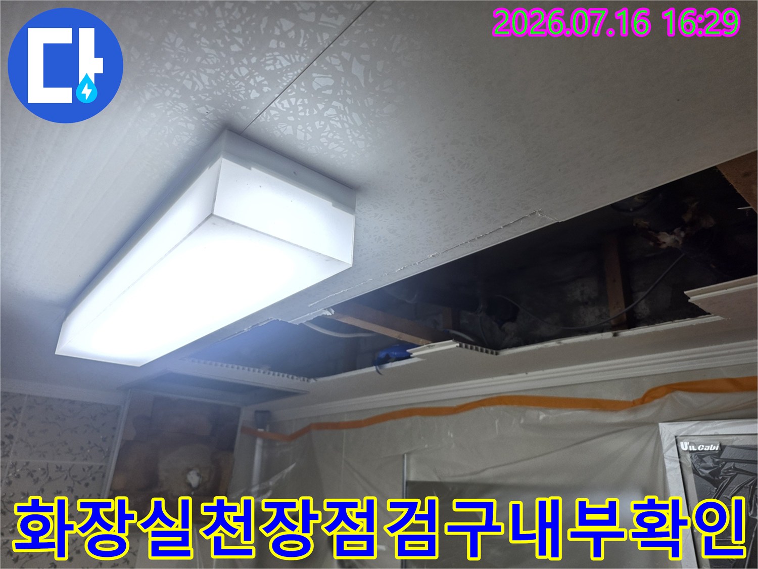 화장실 천장 점검구를 통해 배관과 천장 내부를 확인하는 모습