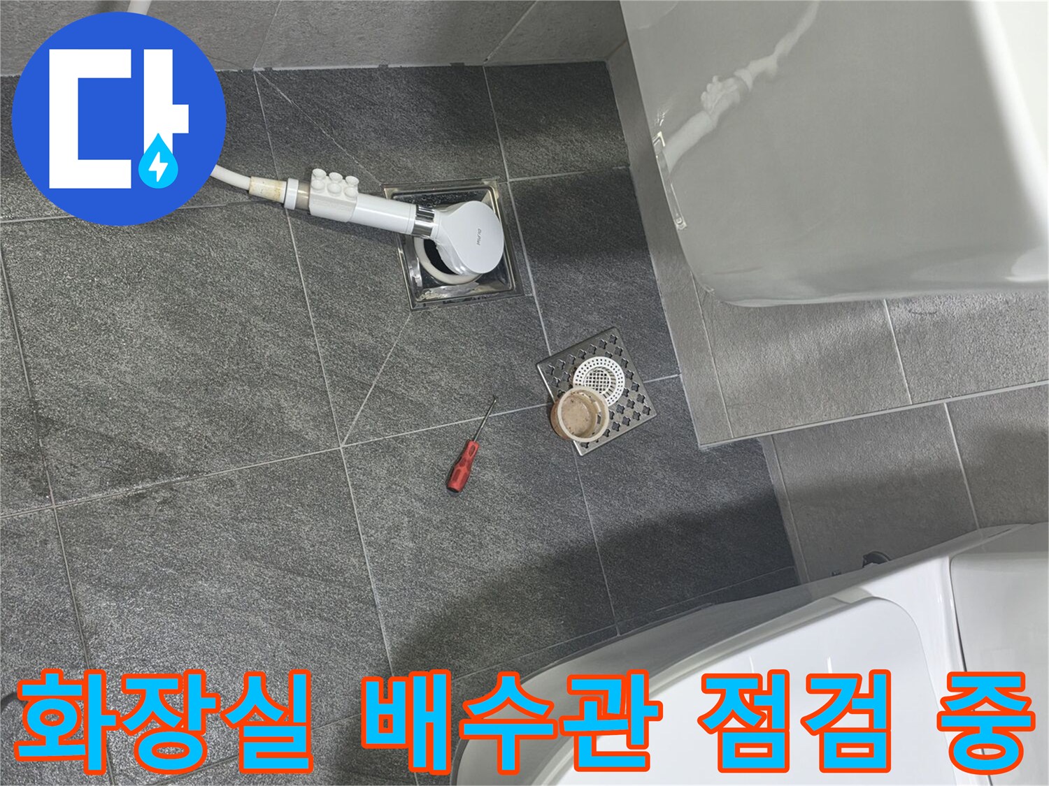 변기 옆 배수구 부근의 배관 연결 상태를 조사하는 현장 사진입니다.