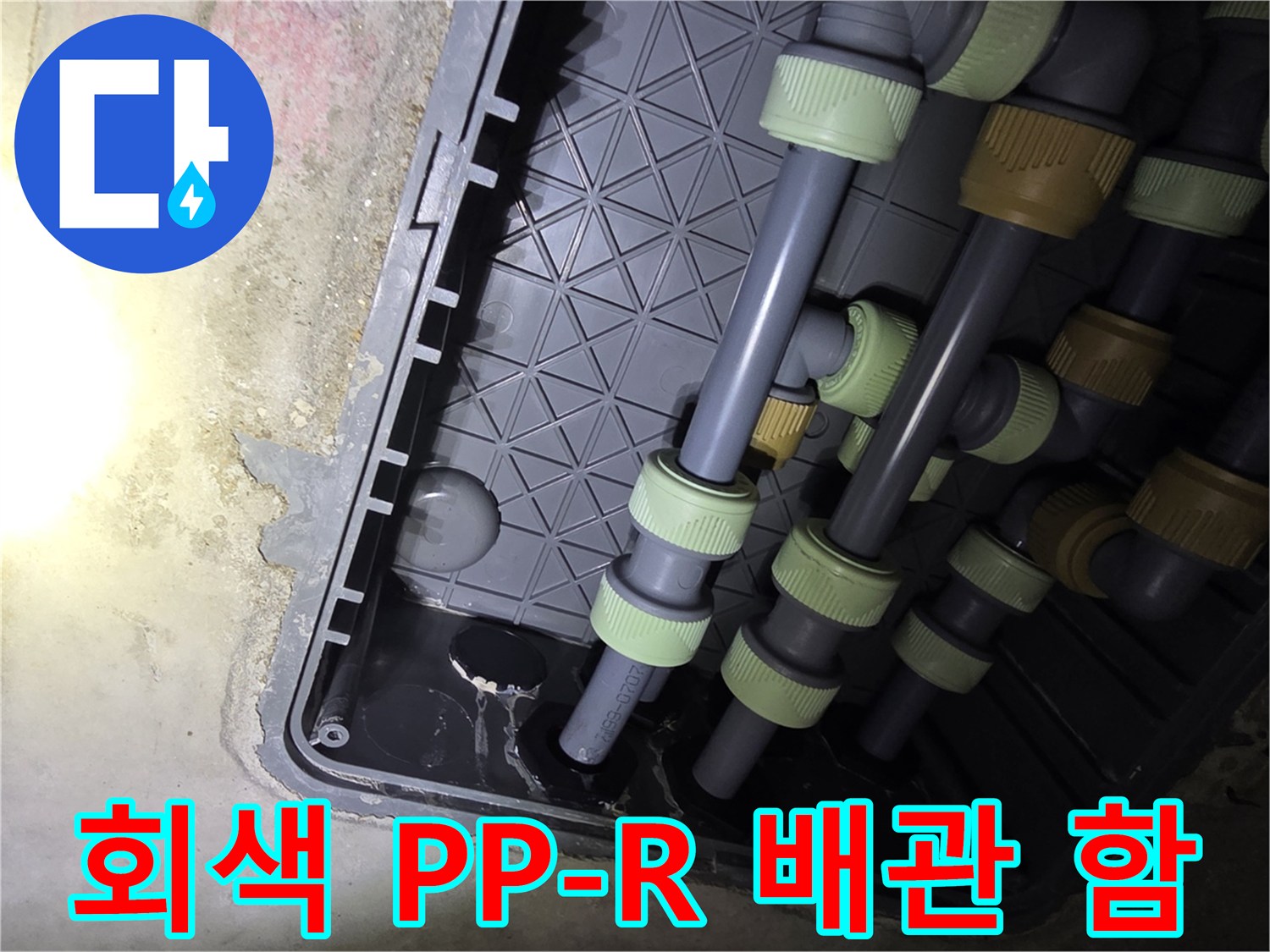 플라스틱 케이스 안에 설치된 회색 수도 배관의 구조적인 모습입니다.