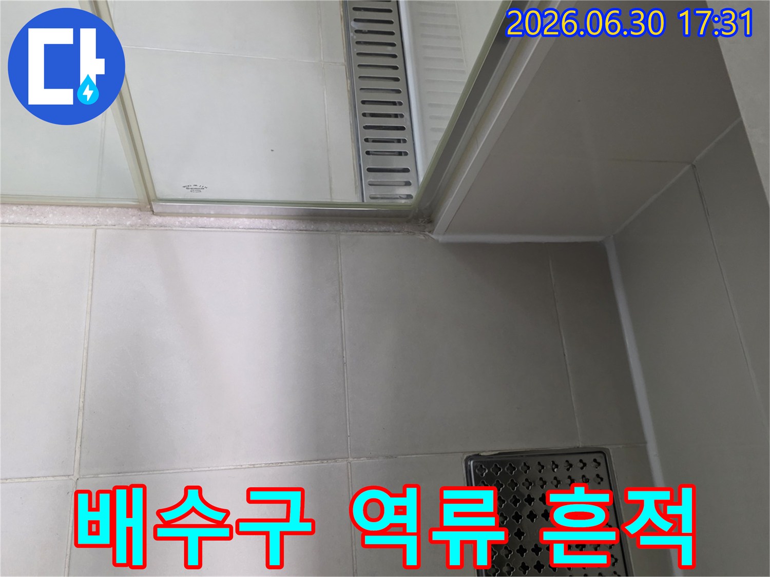욕실 바닥 배수구에서 물이 역류하여-주변에 누수 흔적과 오염이 발생한 모습을 보여주는 이미지