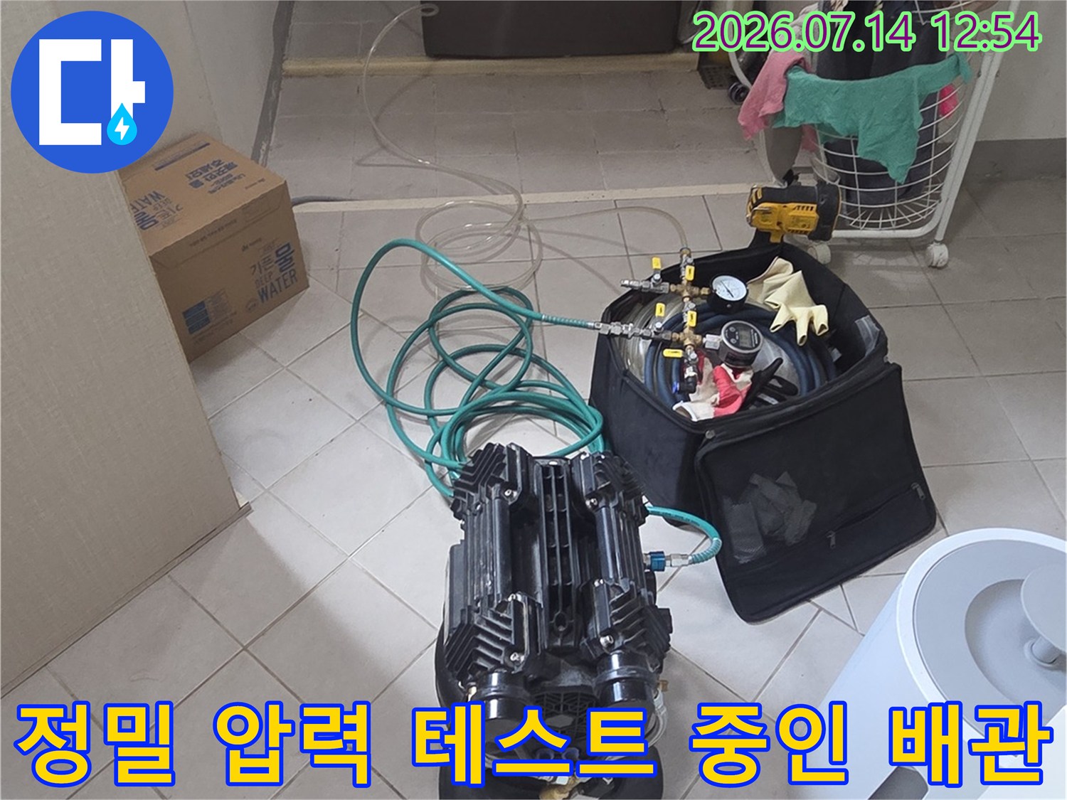 다양한 게이지와 호스를 사용하여 싱크대 아래 수도배관의 누수 여부를 정밀하게 검사하는 모습