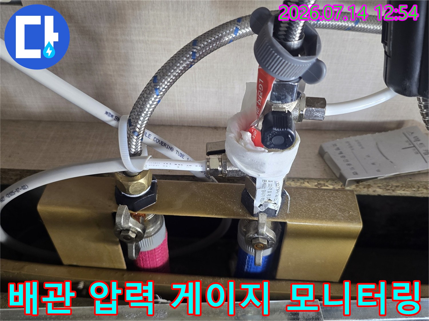 싱크대 밑 배관 시스템에 장비를 연결하여 누수 여부를 실시간으로 확인하는 모습
