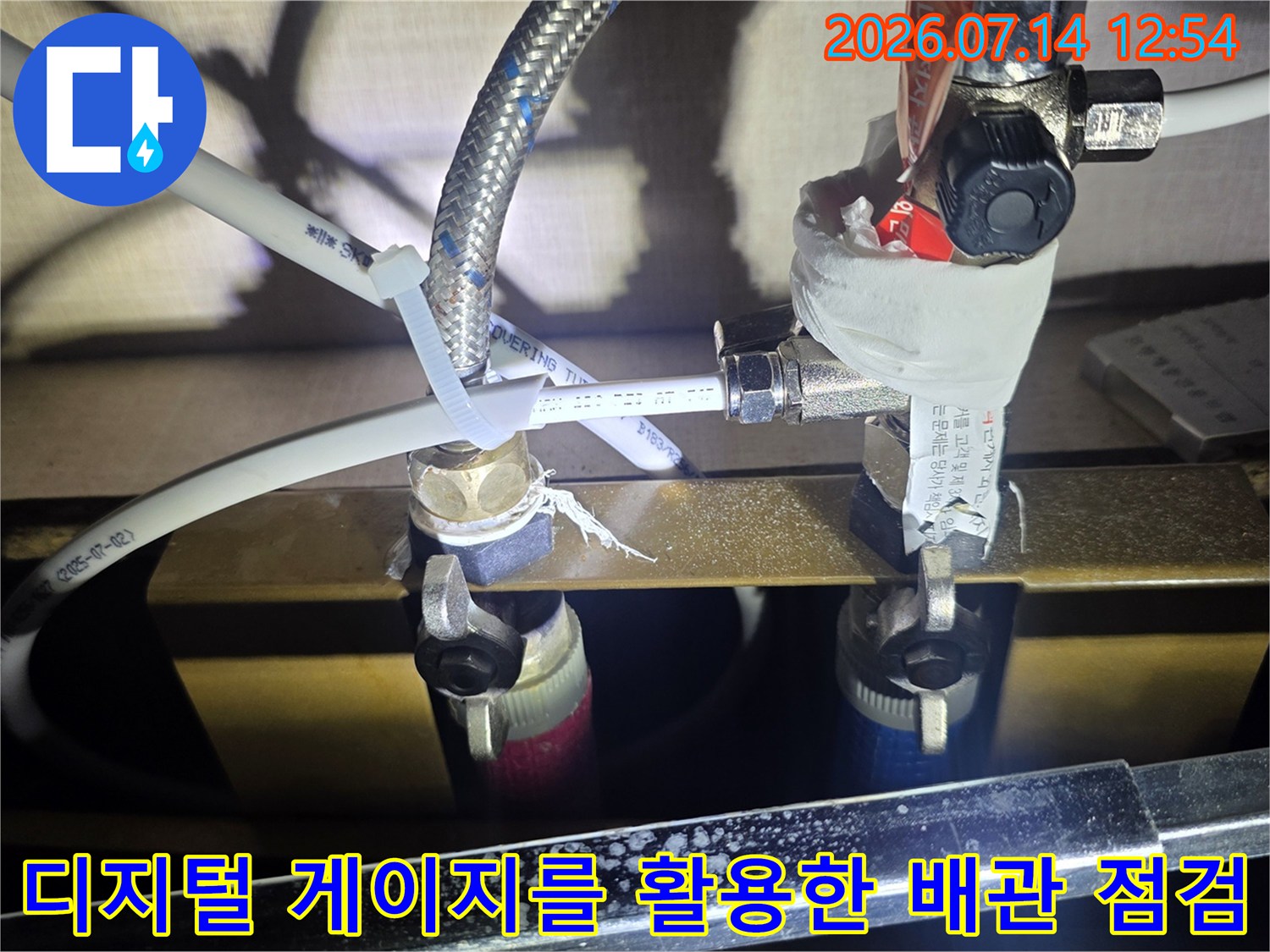 싱크대 하부 노출된 수도 및 온수 배관에 압력계를 연결하여 정밀 진단하는 모습