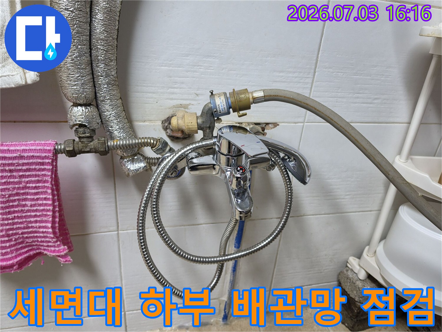 화장실 세면대 밑에 위치한 금속 및 호스 재질의 배관 시스템