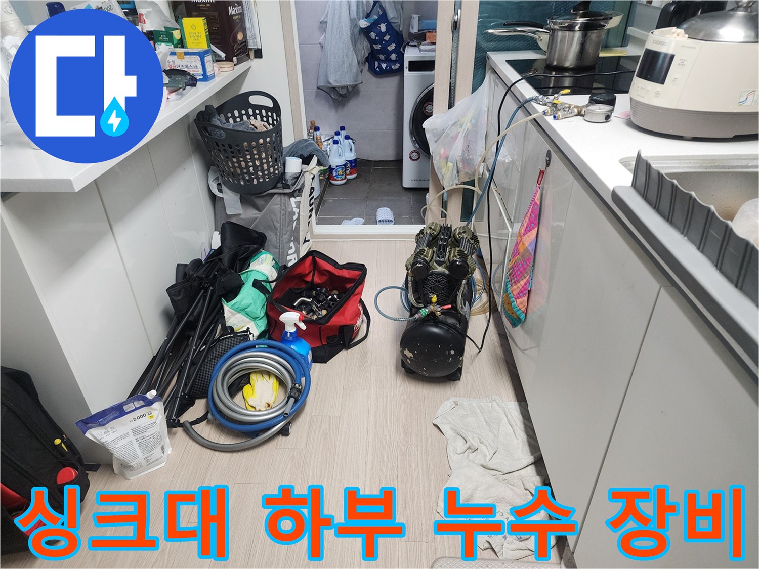 주방 싱크대 아래 좁은 공간에 배치된 압력계와 작업용 호스류