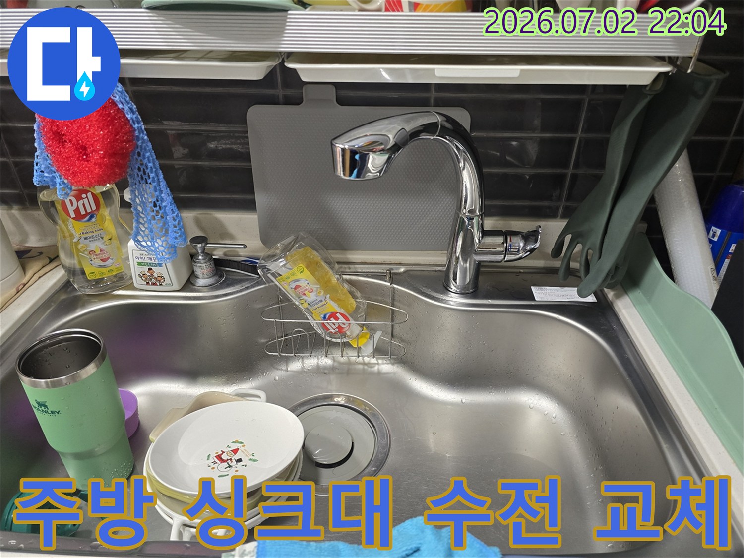 새로 설치된 스테인리스 재질의 주방 싱크대 수전과 세척용품이 놓인 공간