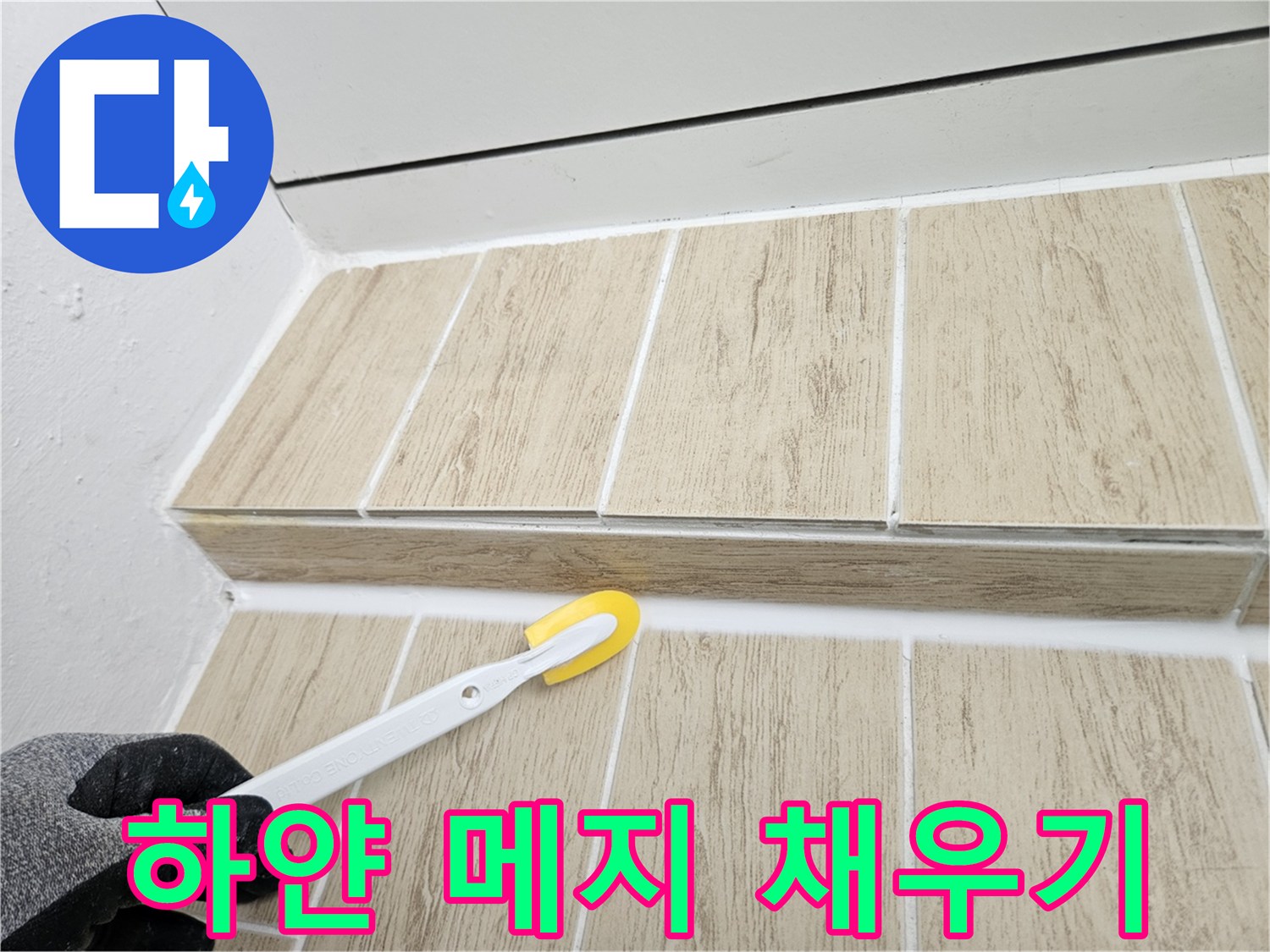 타일 사이 빈 공간에 하얀색 줄눈재를 꼼꼼하게 도포하는 모습