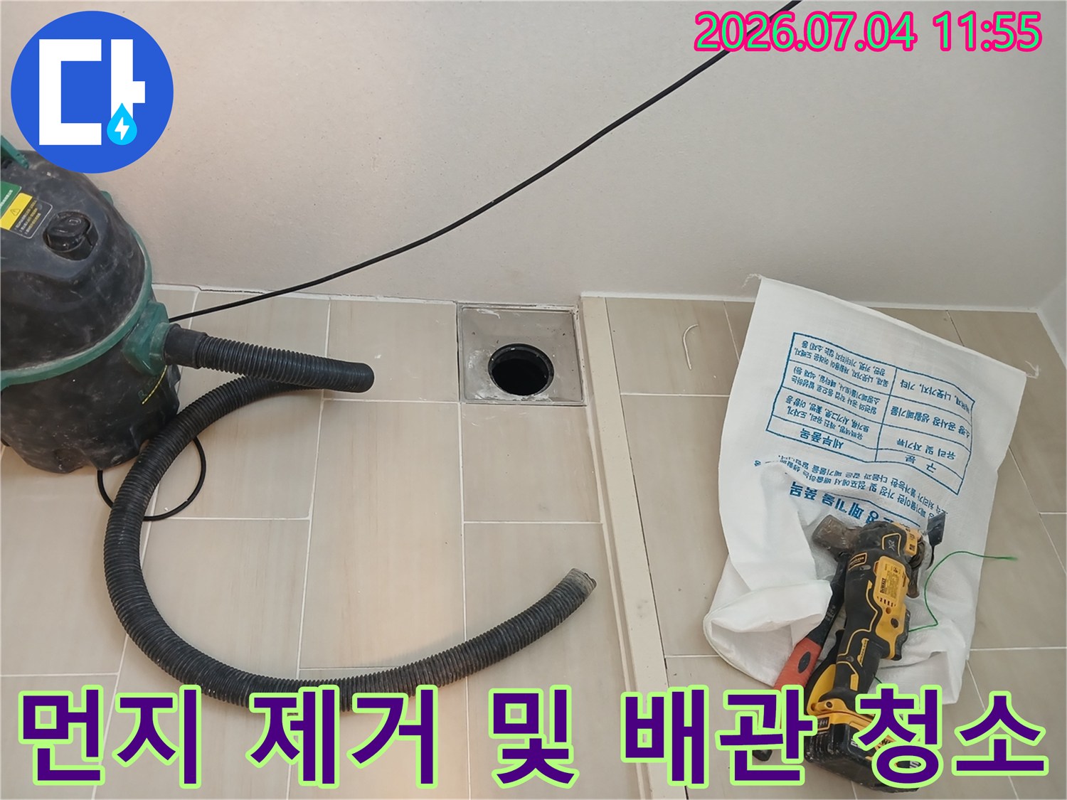 청소기 장비를 사용하여 배수구 주변 이물질을 제거하는 작업 모습