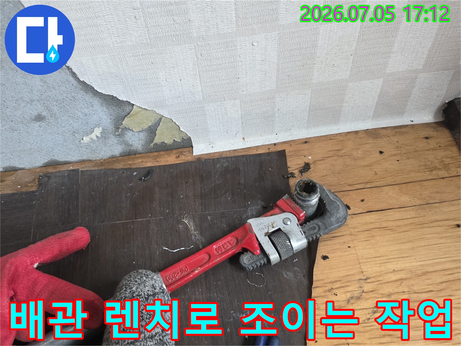 파손된 배관 부위를 전문 렌치를 사용하여 견고하게 체결하는 현장 사진