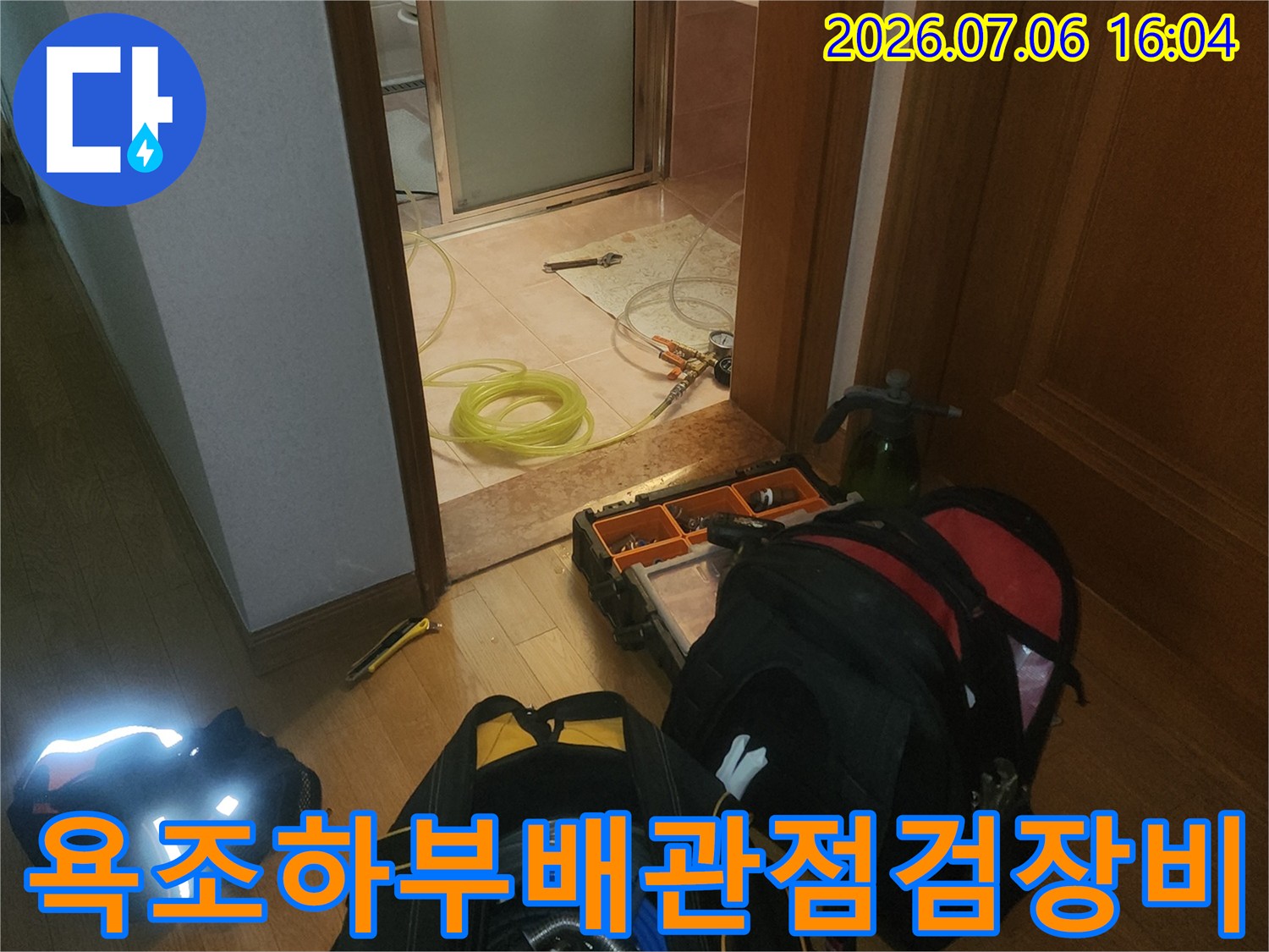 욕조 하부 점검 공간에 배치된 누수 탐지 장비와 배관 점검용 가방