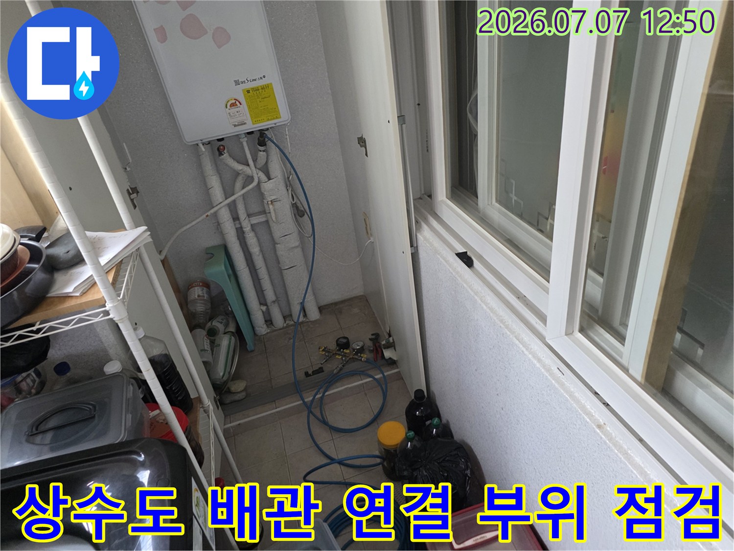다용도실 세면대 아래 노출된 수도 밸브와 배관들의 상태를 정밀하게 진찰하는 장면