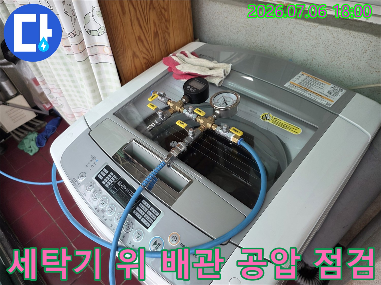 세탁기 위에 설치된 세탁기 배관에 연결된 압력계와 호스 장비