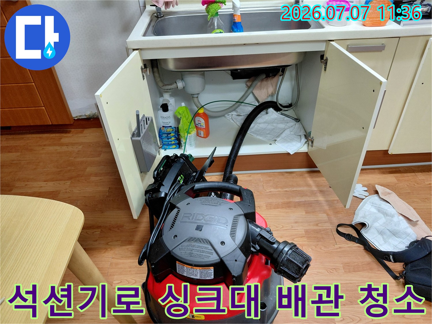 싱크대 하부 공간에서 석션 장비를 사용하여 막힌 하수구를 뚫어내는 과정