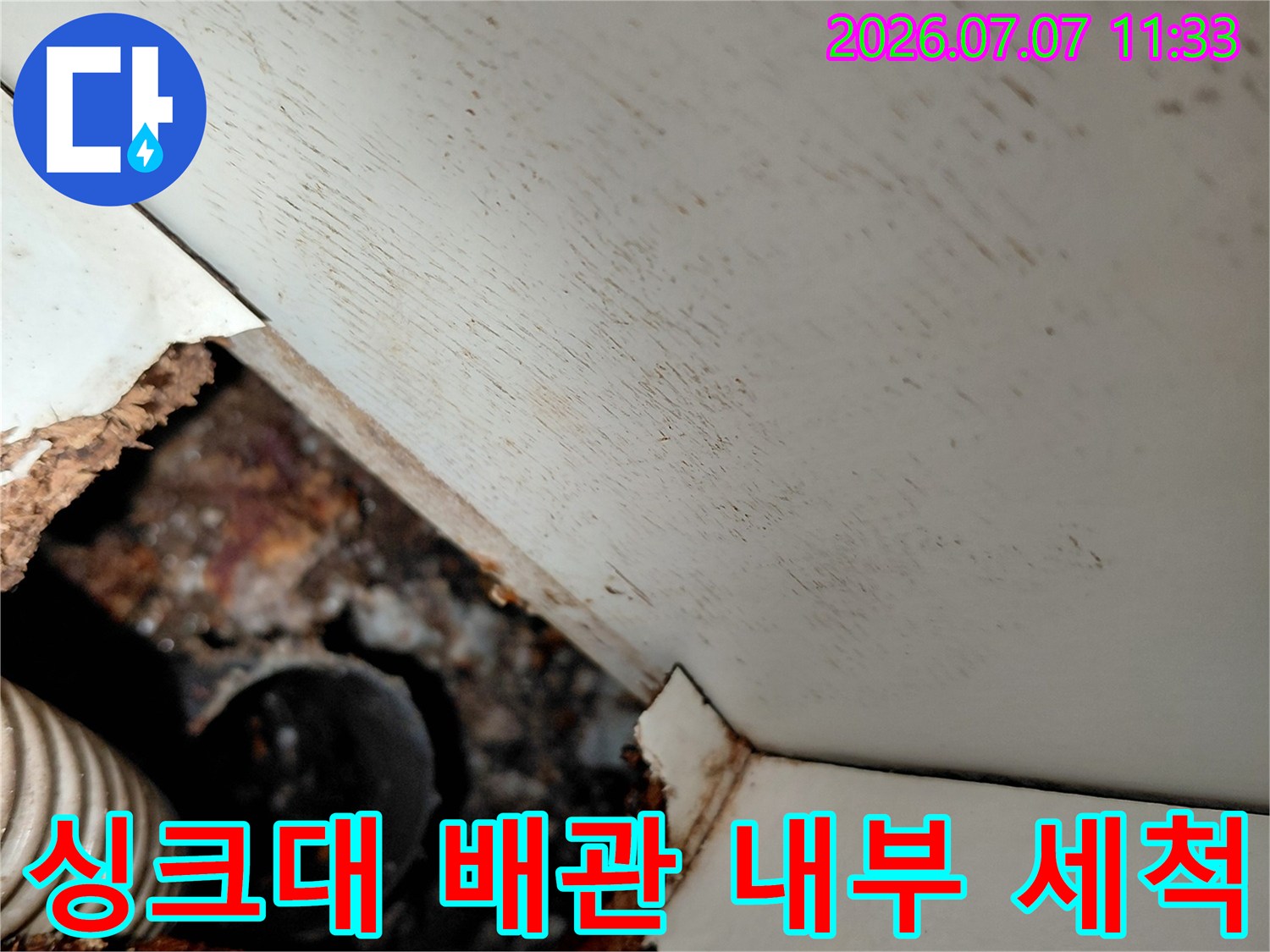 오염된 싱크대 하부 배관과 파손된 마감재를 촬영한 사진