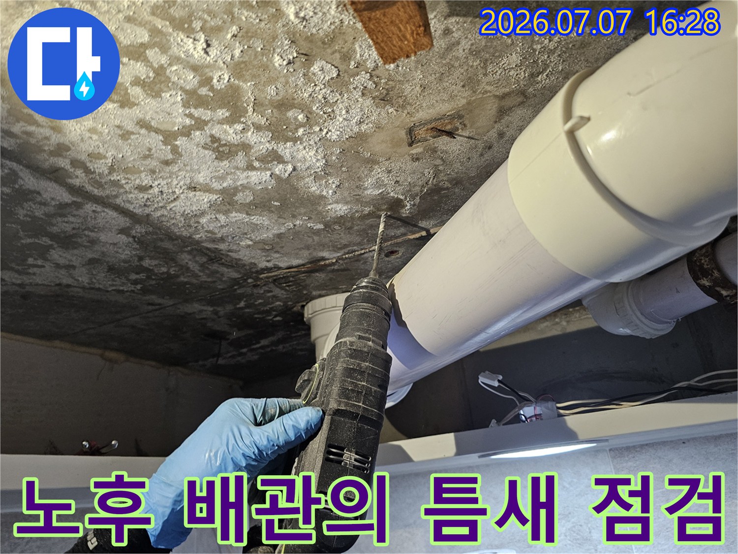 작업자가 장갑을 끼고 천장 내부를 살피며 누수 지점을 파악하는 모습