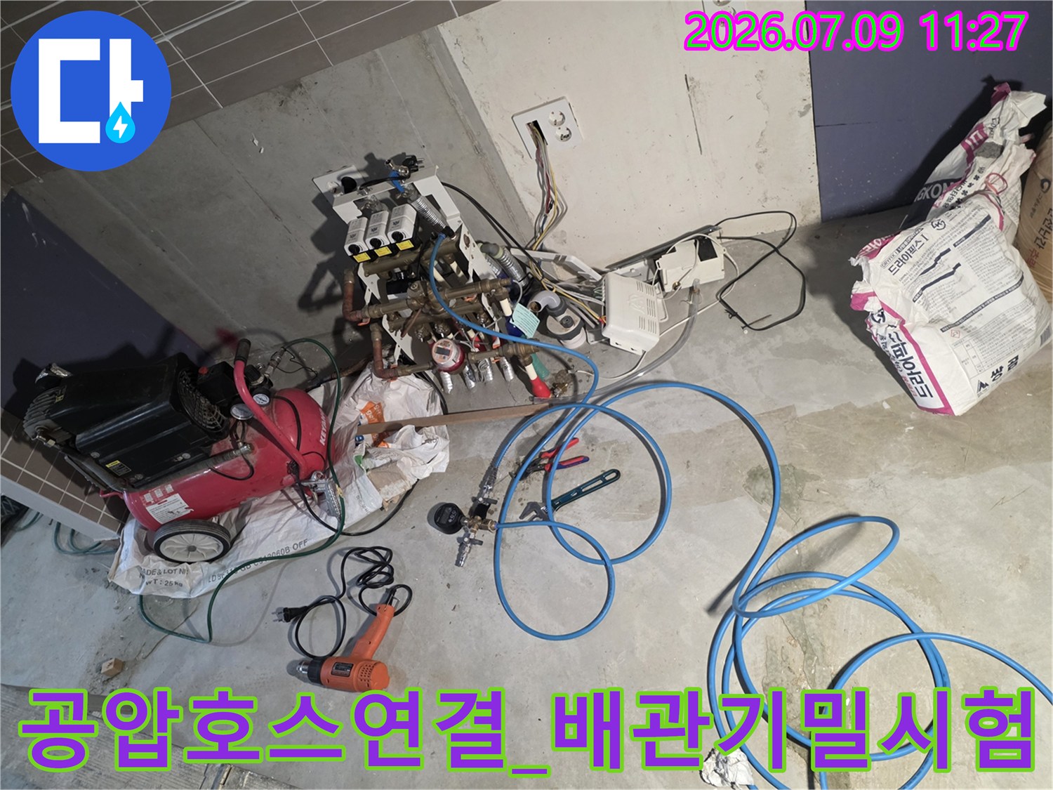 파란색 공압 호스를 배관 분배기에 연결하여 기밀 시험을 진행하는 현장 모습