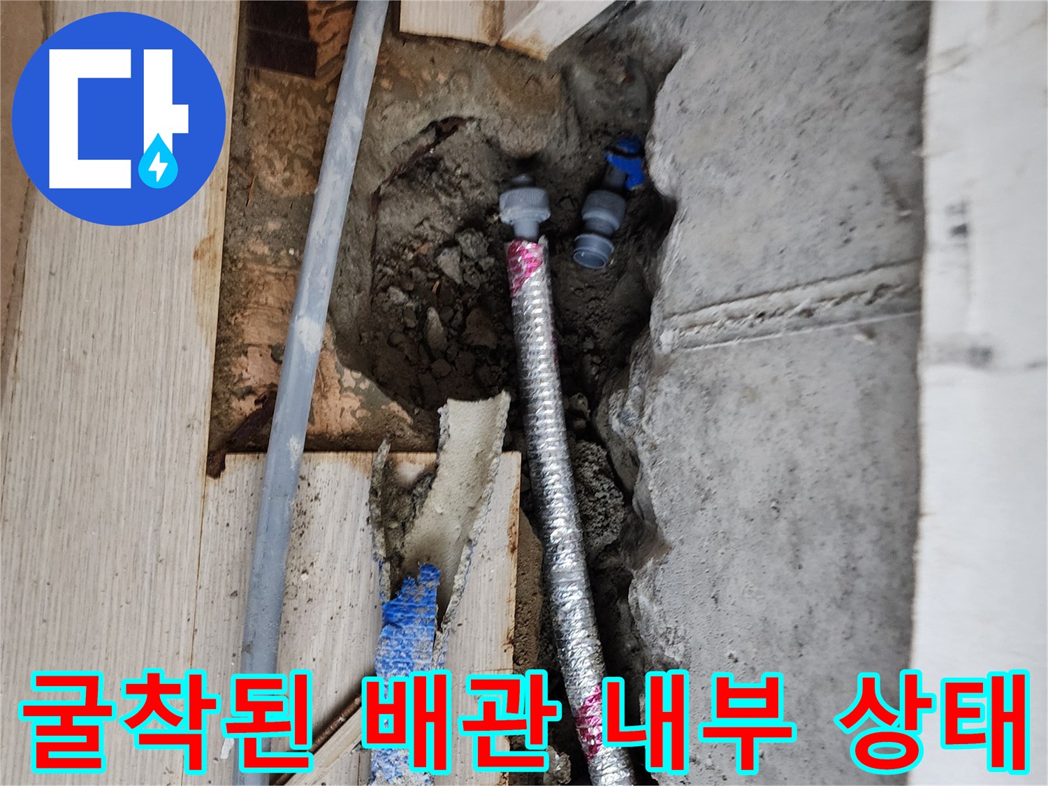 바닥 굴착 후 드러난 은색 주름관과 파란색 배관의 누수 여부 점검
