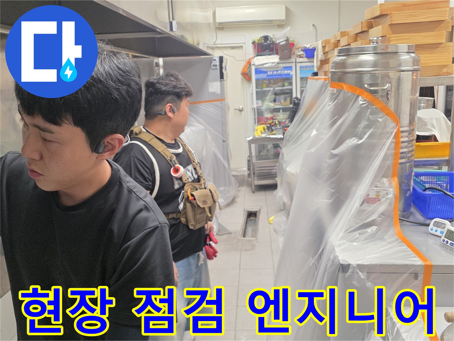 주방 내부에서 배관 문제를 확인하고 있는 작업자 사진입니다.