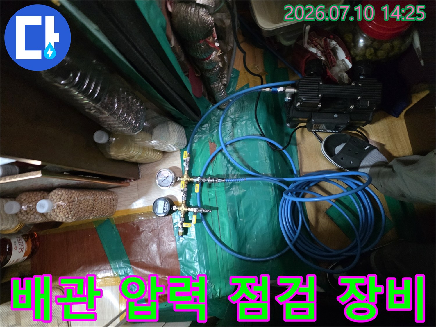 배관 시스템에 연결된 파란색 호스와 디지털 측정기를 활용한 누수 정밀 탐지 과정