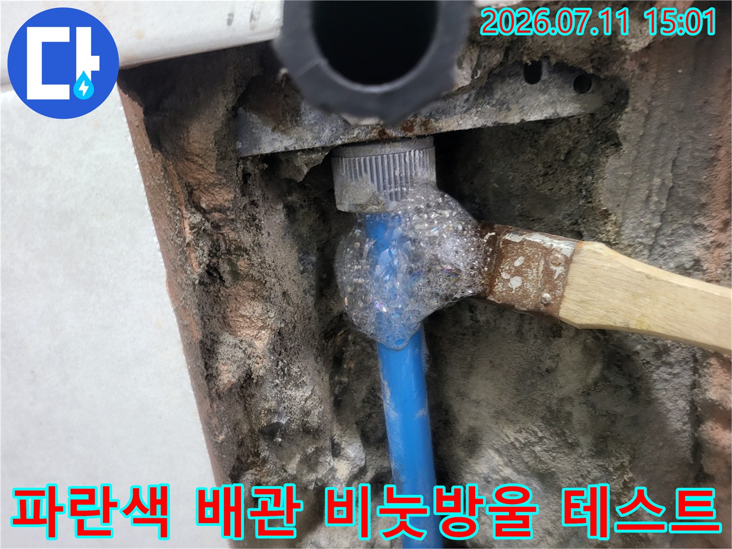 노출된 파란색 배관 부속에 거품을 묻혀 누수 여부를 정밀하게 확인하는 장면