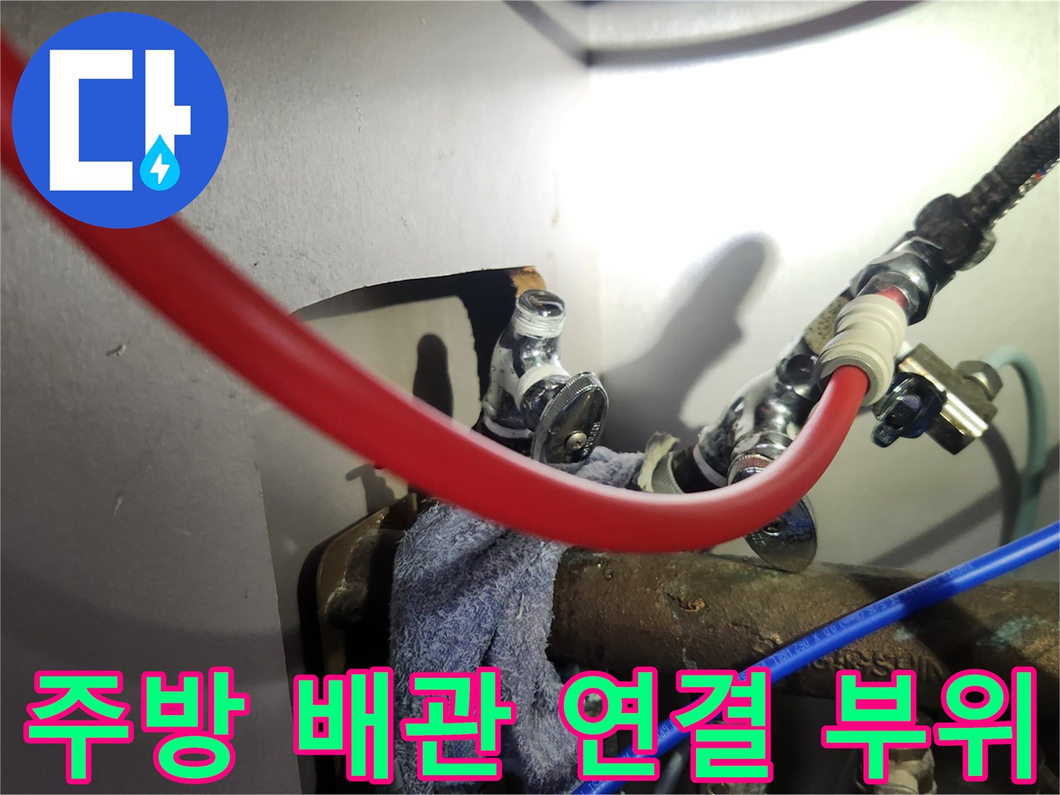 싱크대 하부장 내부의 붉은색 온수 호스와 은색 앵글밸브 연결 상태