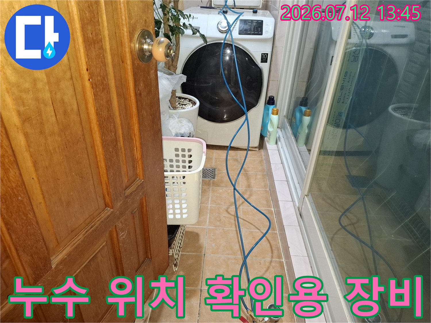 세탁기 옆 바닥에 배치된 파란색 호스와 공구들을 통해 누수 지점을 정밀하게 추적하는 모습