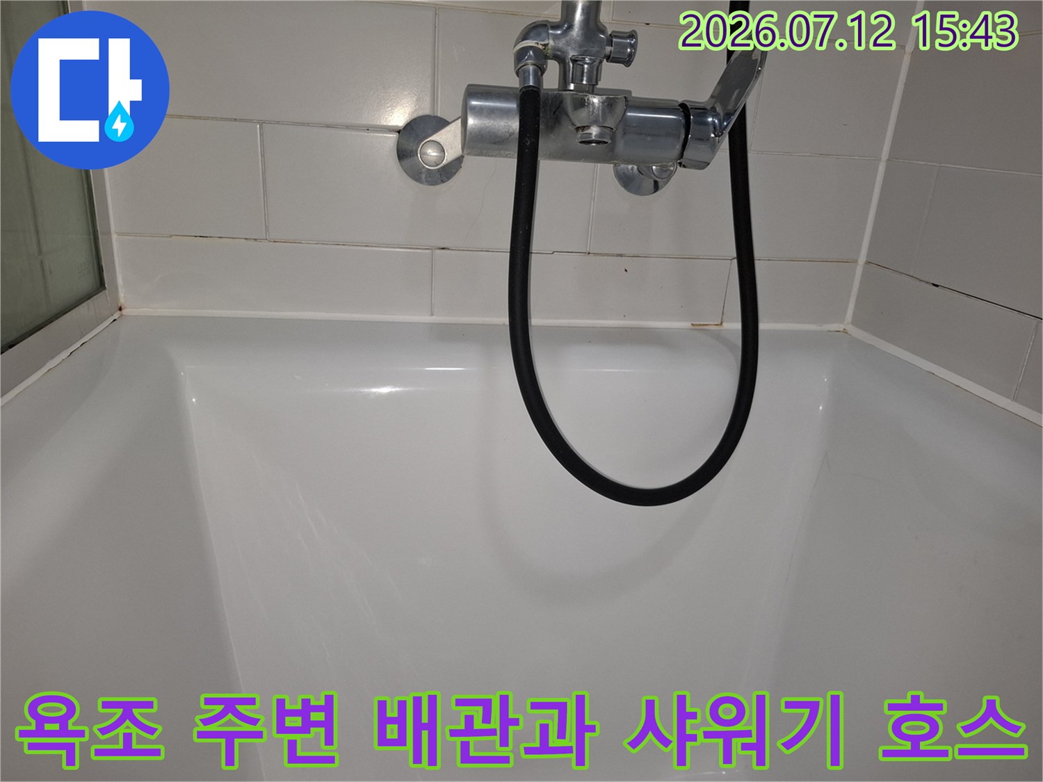 욕조 안쪽으로 연결된 검은색 샤워기 호스와 금속제 수전 부속 구성