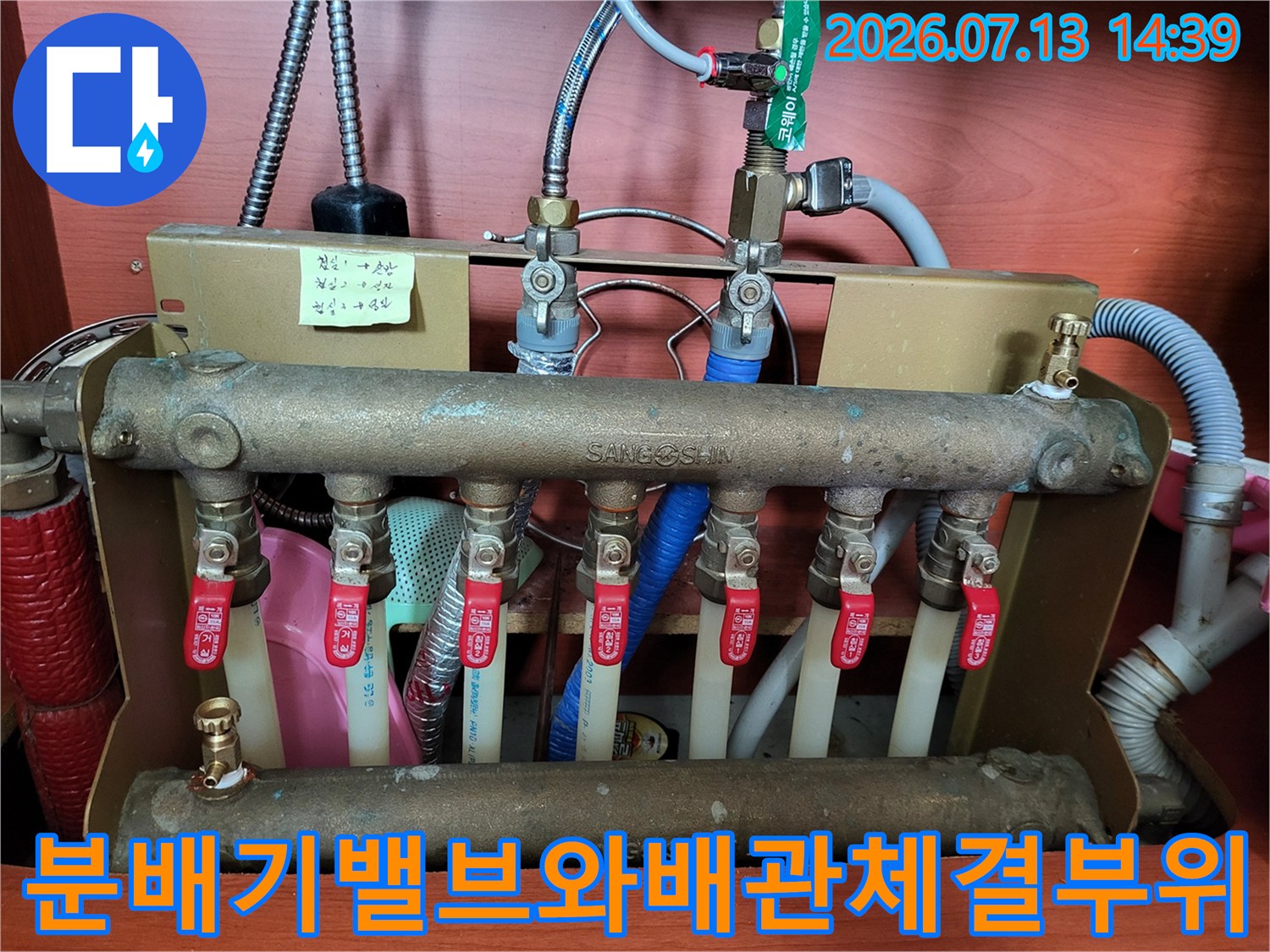 금속제 분배기의 빨간색 밸브들과 상단 파란색 배관 연결부 모습
