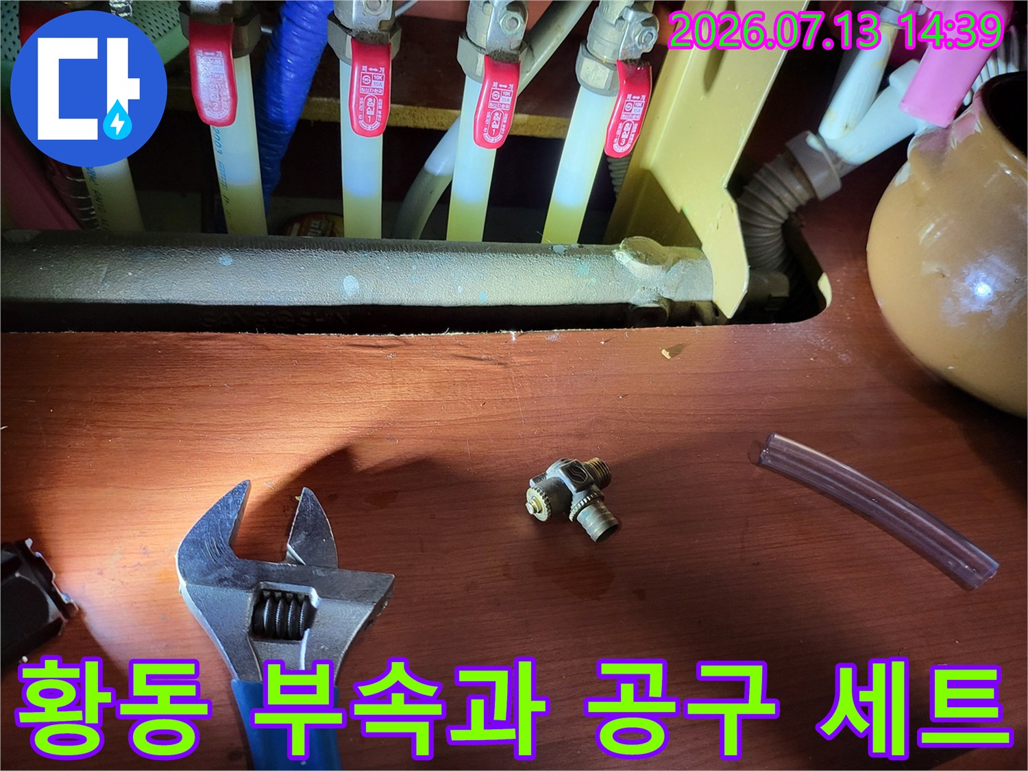 분배기에서 제거된 황동색 티자형 연결 부품과 작업용 몽키스패너 사진