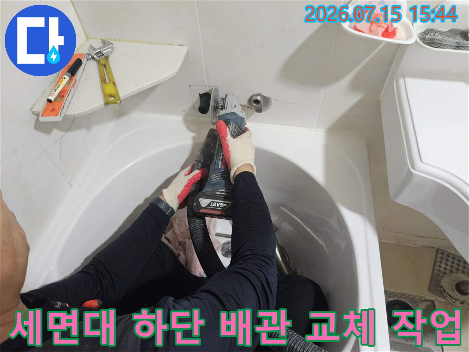 손상된 세면대 아래 온수 배관을 제거하고 새 연결부로 수리하는 현장 사진