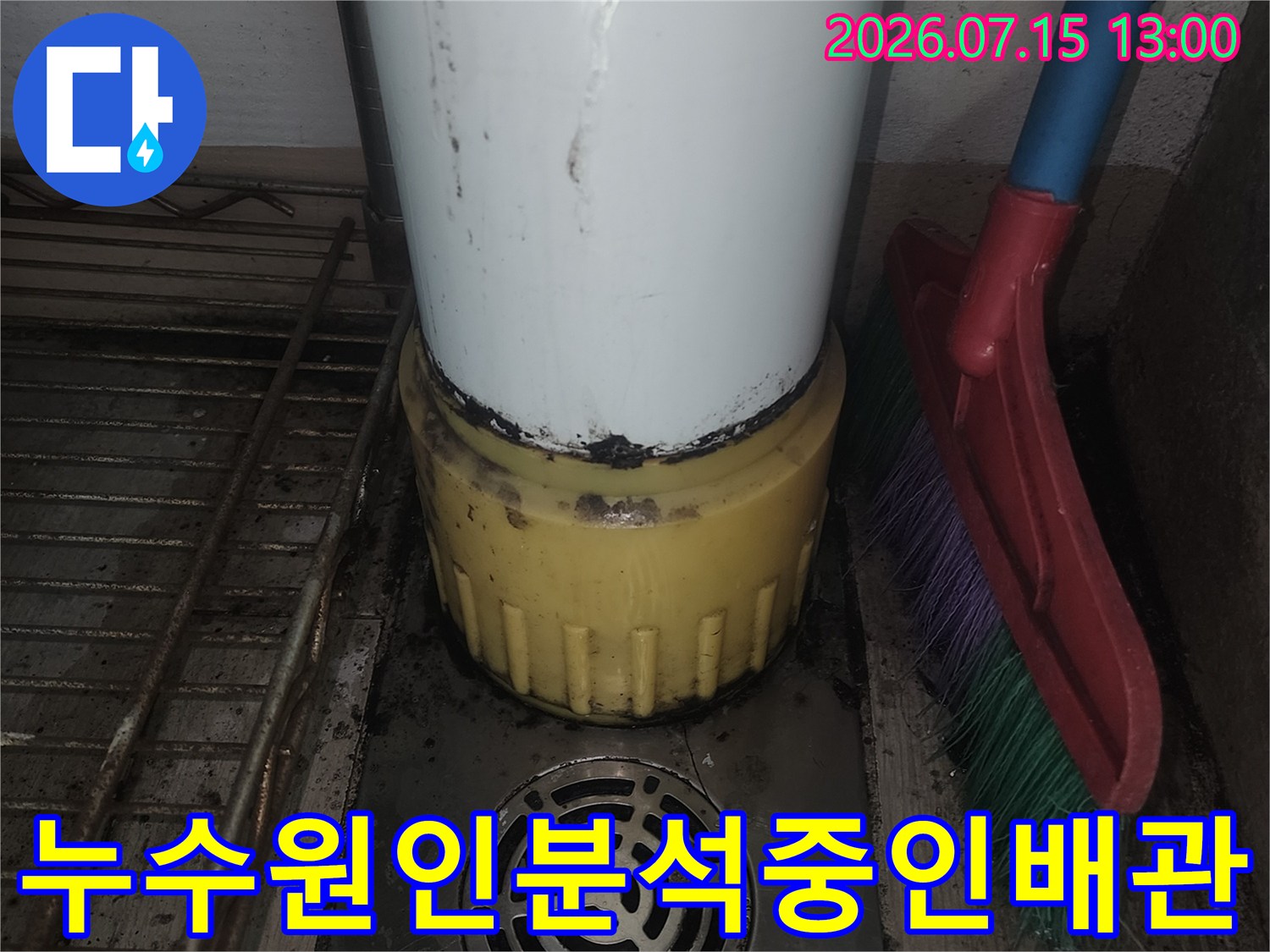 노란색 캡이 씌워진 흰색 배관과 금속 재질의 배수구 통로