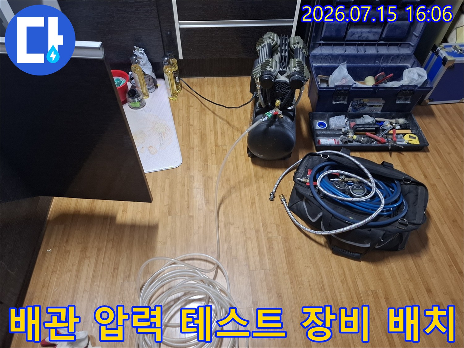 검정색 가스 탱크와 파란색 호스가 포함된 누수 탐지 세트가 거실 바닥에 놓인 모습