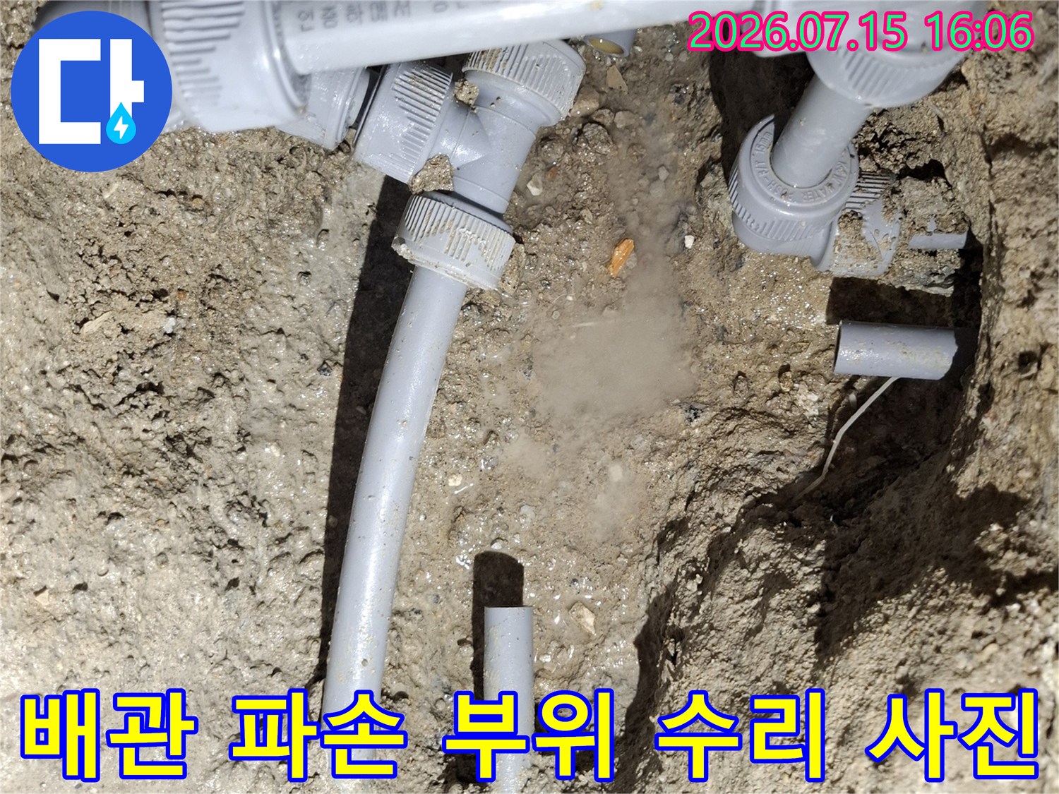 땅속에 노출된 회색 플라스틱 수도 배관의 연결 부위를 새 제품으로 교체한 모습