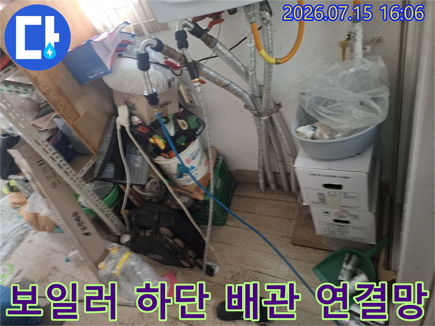 은색 금속 관과 파란색 플라스틱 관이 교차하며 설치된 보일러 하부-현장 점검 사진