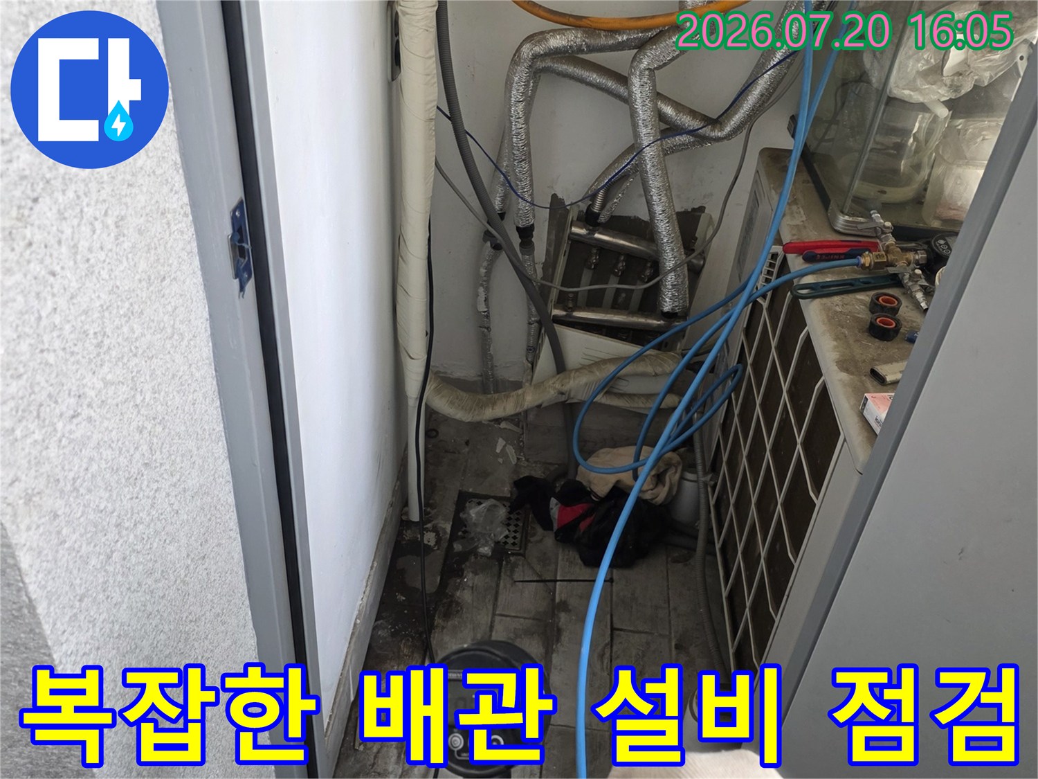 싱크대 아래 복잡하게 얽힌 배관과 계량기를 확인하는 전문 장비 점검