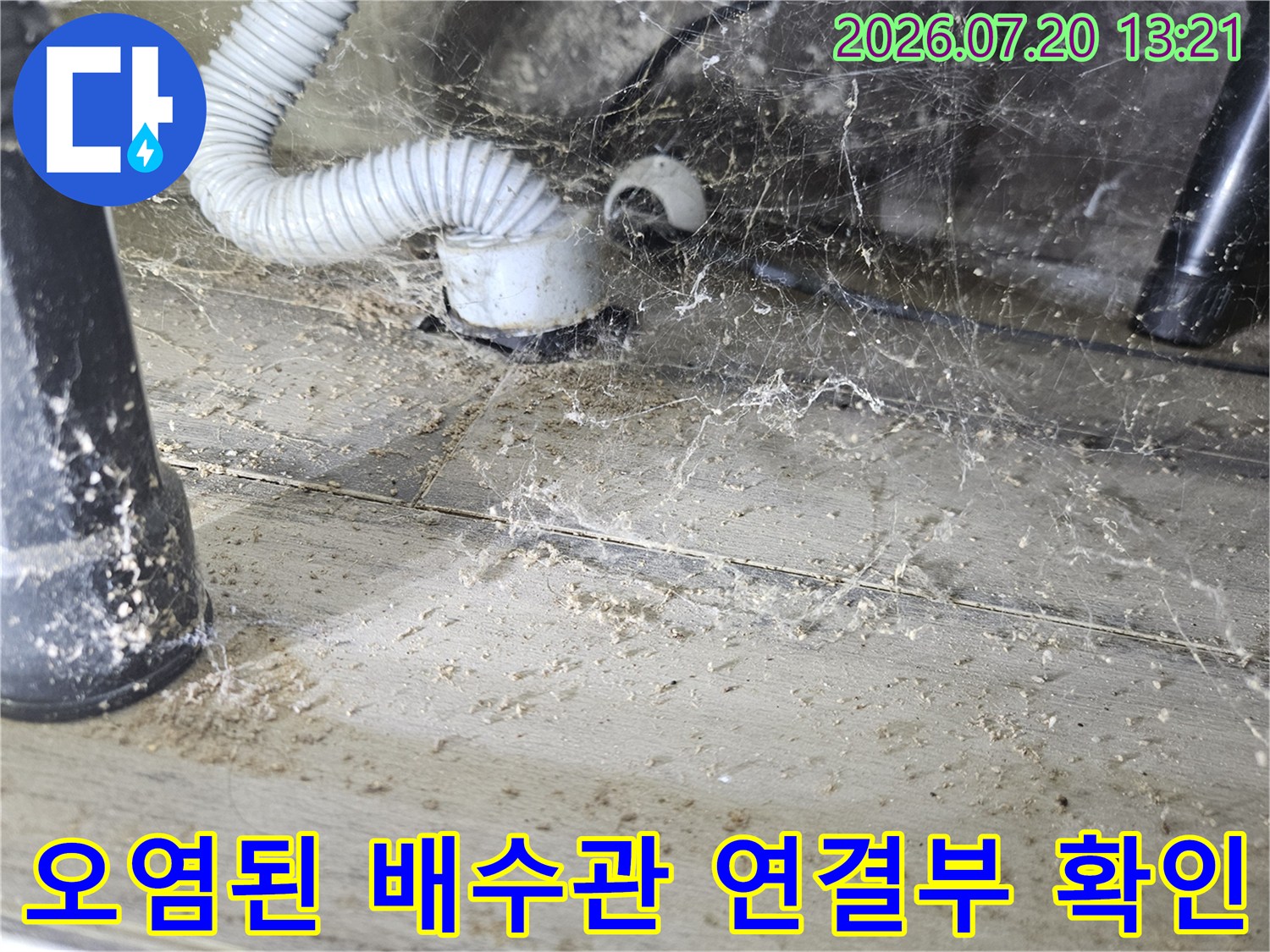 먼지와 습기로 인해 변색된 세탁용 배수 호스 및 하부 연결 구간의 모습