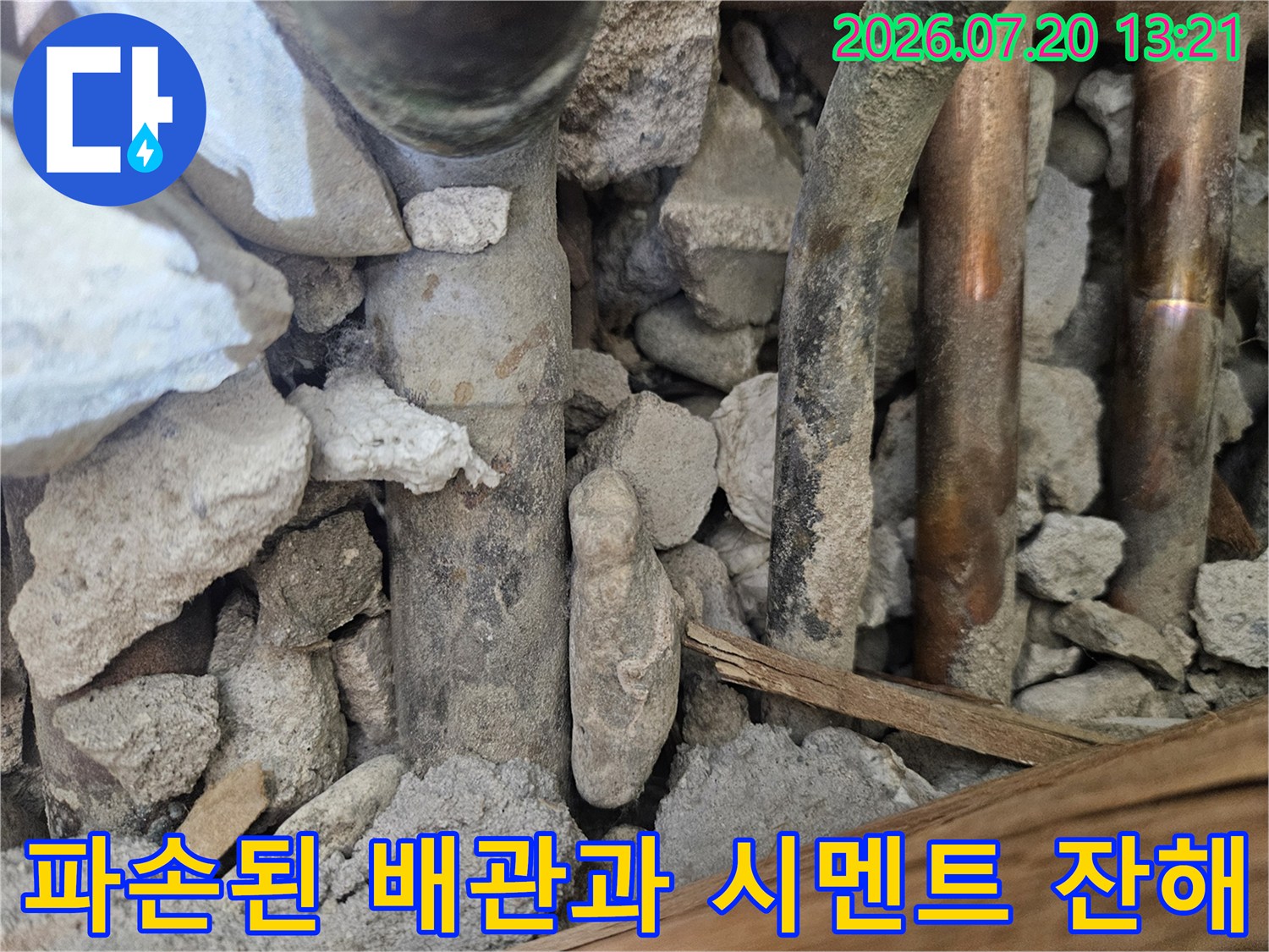 오래된 수도 배관 주변의 파손된 시멘트 조각들과 노출된 관들