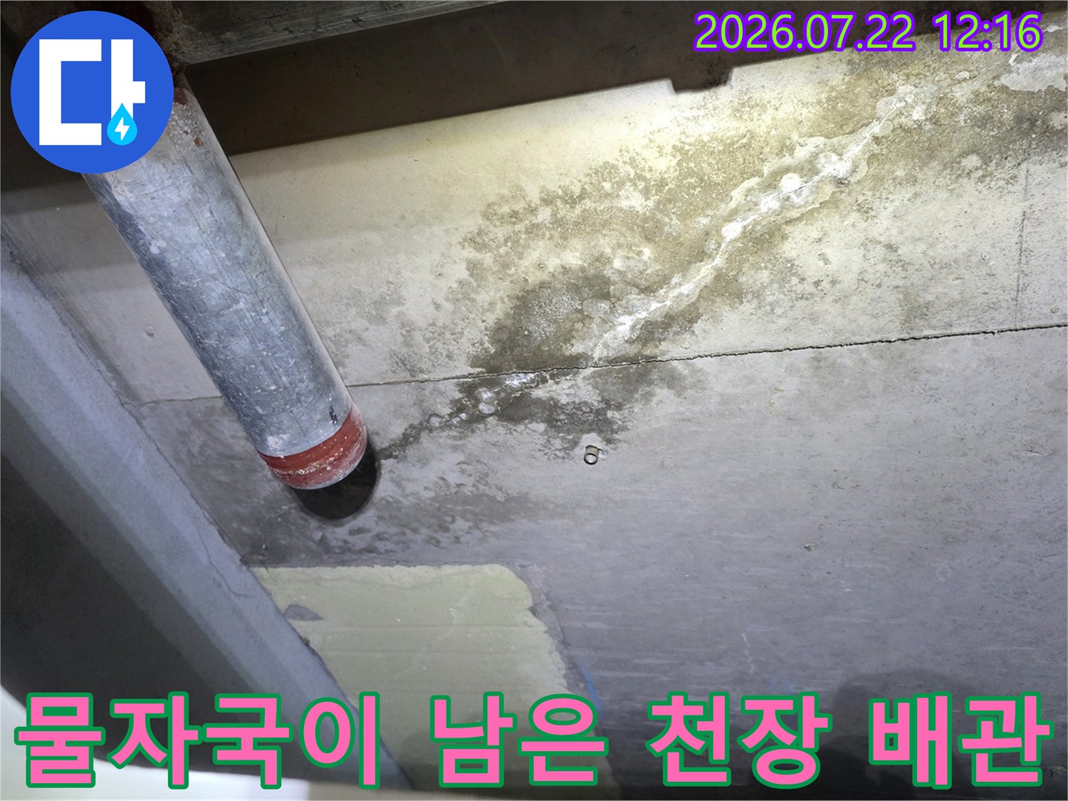 회색 콘크리트 천장에 설치된 배관과 그 주변으로 번진 누수 오염 흔적